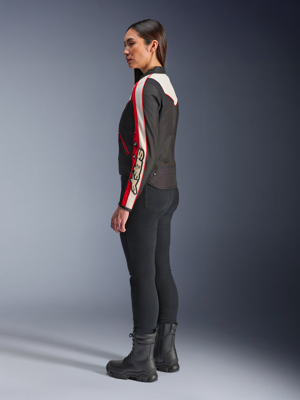 Giacca Alpinestars Stella T-Dyno WR, giacca da moto in tessuto per donna, nero ecru e rosso vivace, design di ispirazione vintage con logo Astars sulla manica, indossata con pantaloni neri slim e stivali neri, vestibilità corta da biker per la guida urbana
