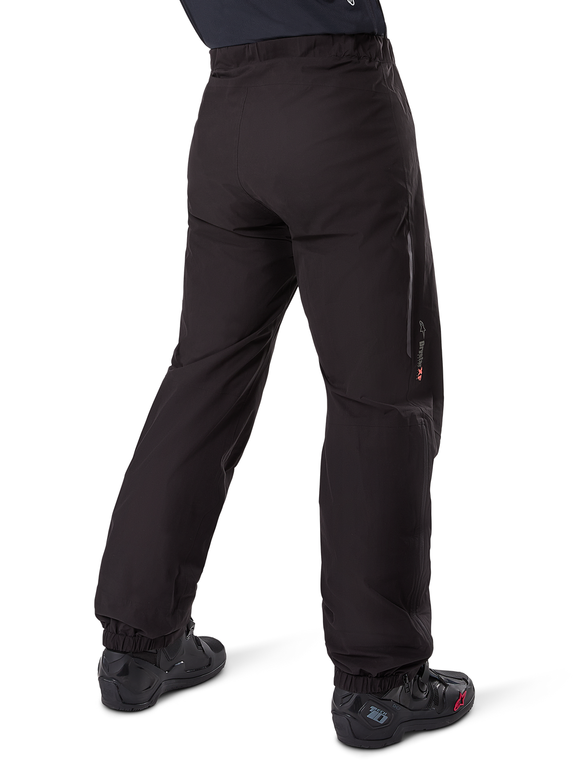 Alpinestars Amt-8 Stretch Drystar® XF Pant Liner, nero, vista posteriore della fodera impermeabile indossata sopra stivali da moto neri, con marchio Drystar XF sulla parte inferiore della gamba, polsini elasticizzati e materiale elasticizzato leggero per adventure touring.