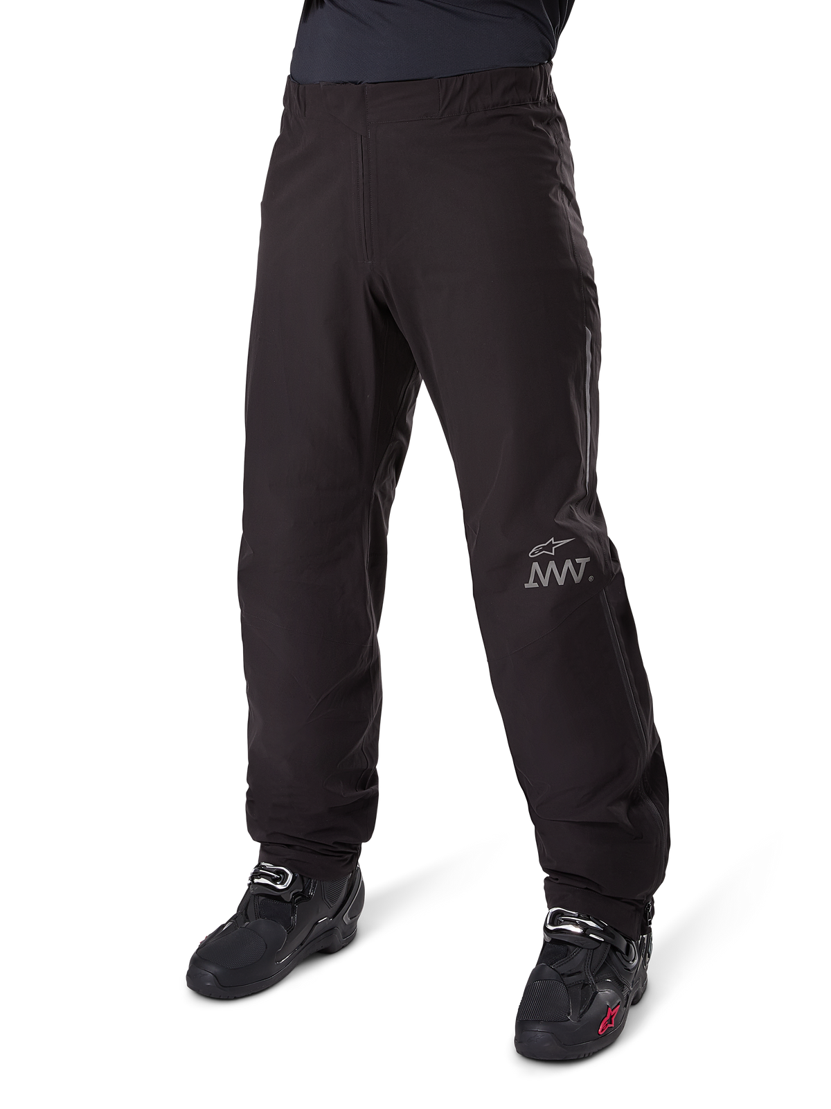 Fodera per pantaloni Alpinestars Amt-8 Stretch Drystar® XF, nero, costruzione in tessuto tecnico impermeabile ed elasticizzato con logo AMT argento, indossata con stivali da moto neri, componente per abbigliamento moto adventure touring.