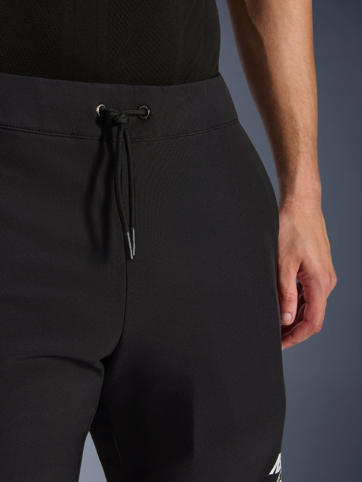 Pantaloni Alpinestars Aeroshell, pantaloni da moto in softshell nero, vista ravvicinata della vita elastica e della chiusura con cordoncino, design moderno e minimalista, costruzione in tessuto resistente per il touring casual