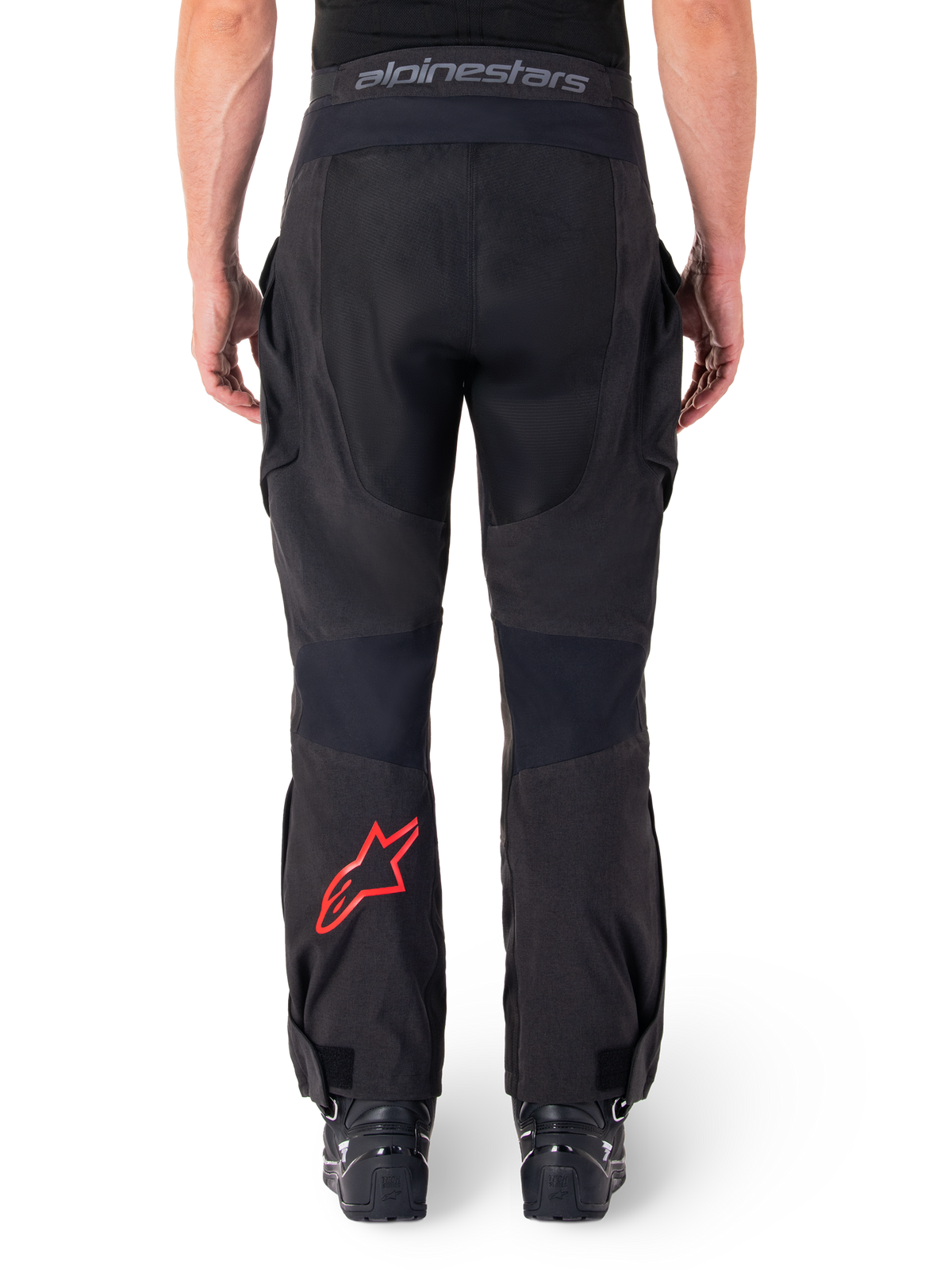 Alpinestars Hyde XT Drystar® Pants, pantaloni da moto adventure, nero con logo a stella rosso sulla parte inferiore della gamba, vista posteriore, design enduro sopra lo stivale con pannelli in tessuto resistente e fascia in vita con marchio