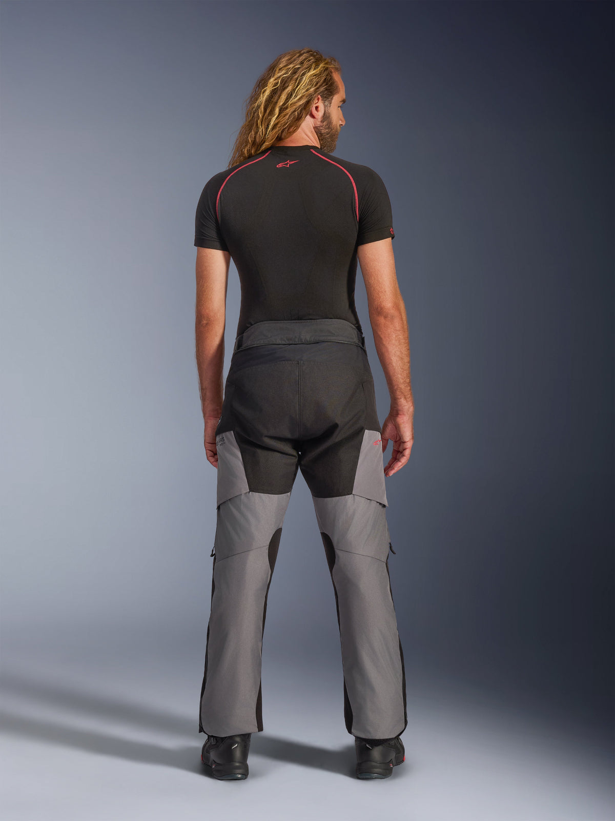 Pantaloni Alpinestars Andes V4 Drystar®, pantaloni da moto adventure, nero e grigio scuro, vista posteriore indossata da un modello, con pannelli in tessuto rinforzato sulla seduta e sulle gambe, progettati per il touring e il commuting in ogni condizione climatica