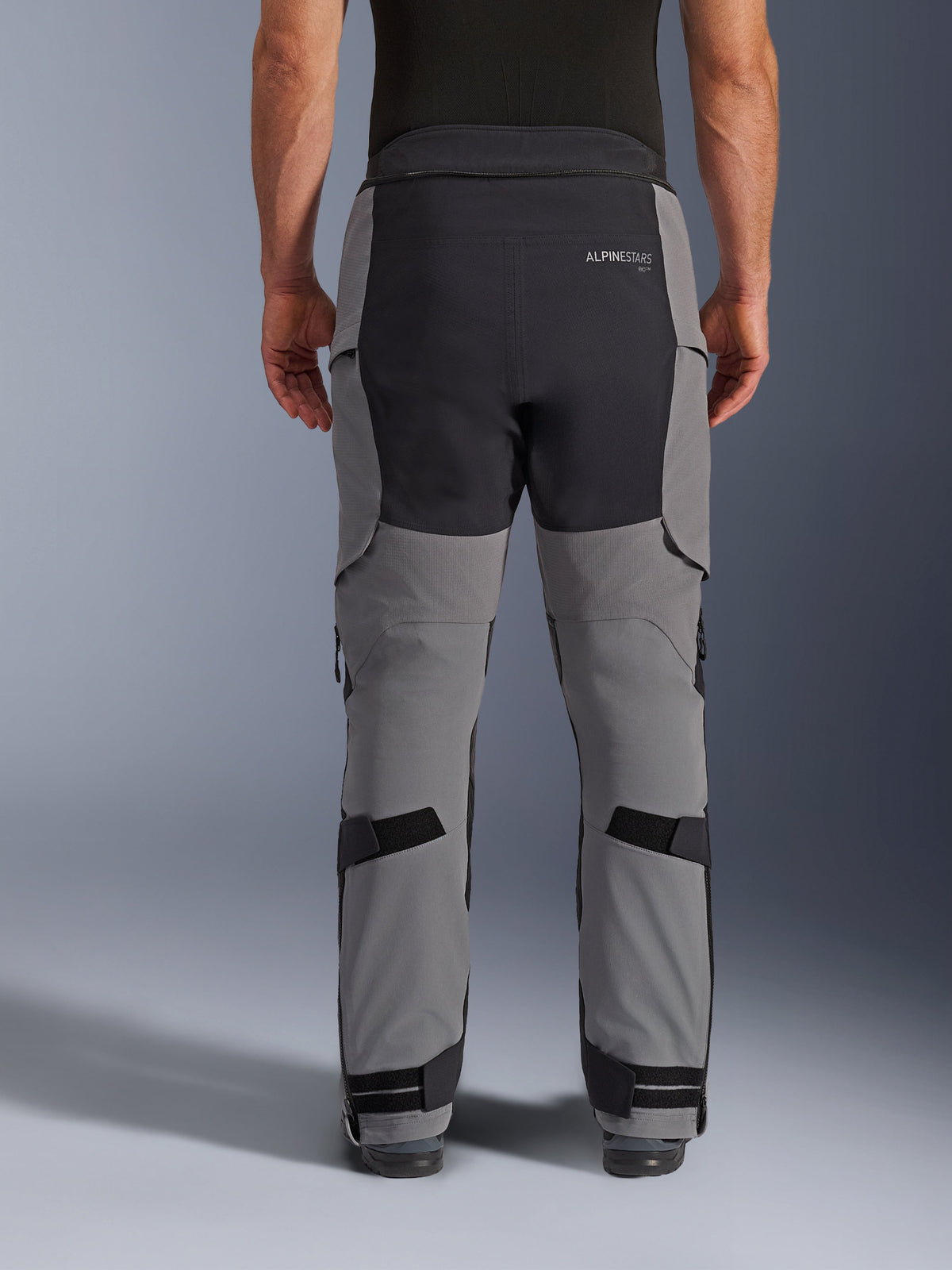 Alpinestars Andes Pro Drystar® XF Pants, vista posteriore, grigio scuro e nero, pantaloni da moto adventure con pannelli rinforzati neri sulla seduta, logo Alpinestars posteriore e cinghie regolabili dietro le ginocchia e alle caviglie per una vestibilità sicura.
