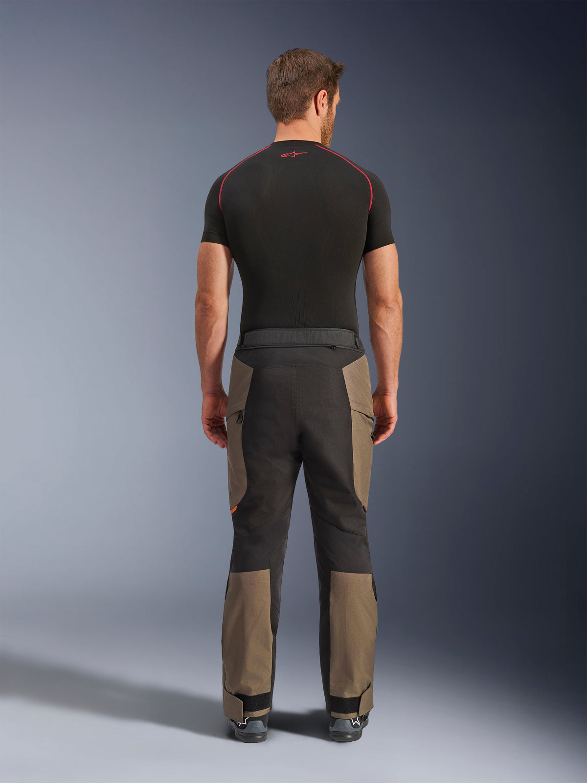 Alpinestars Pantaloni Cusco Drystar®, pantaloni da moto adventure, Walnut Black, vista posteriore con pannelli marroni e neri, robusta costruzione in ripstop, indossati con una maglia tecnica nera