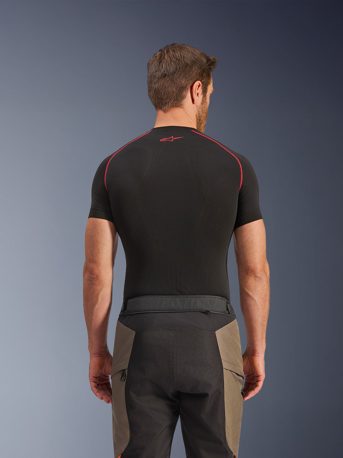 Alpinestars Pantaloni Cusco Drystar®, pantaloni da adventure touring, Walnut Black, vista posteriore con dettagli della vita e design color-block, indossati con un base layer nero a maniche corte con cuciture rosse e logo