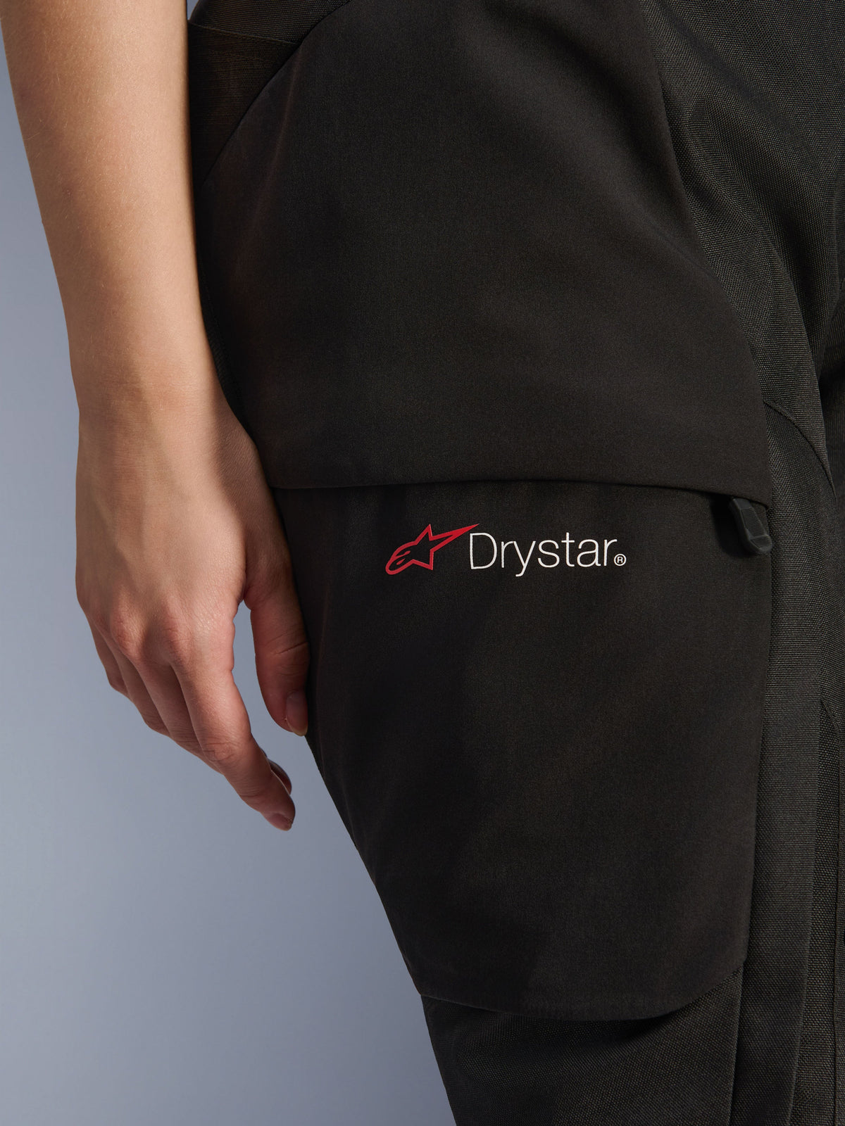 Alpinestars Stella Andes V4 Drystar® Pants da donna, pantaloni da moto adventure, nero, primo piano della zona della coscia con logo Drystar e icona a stella rossa, materiale tessile resistente con tasca cargo e dettaglio della zip