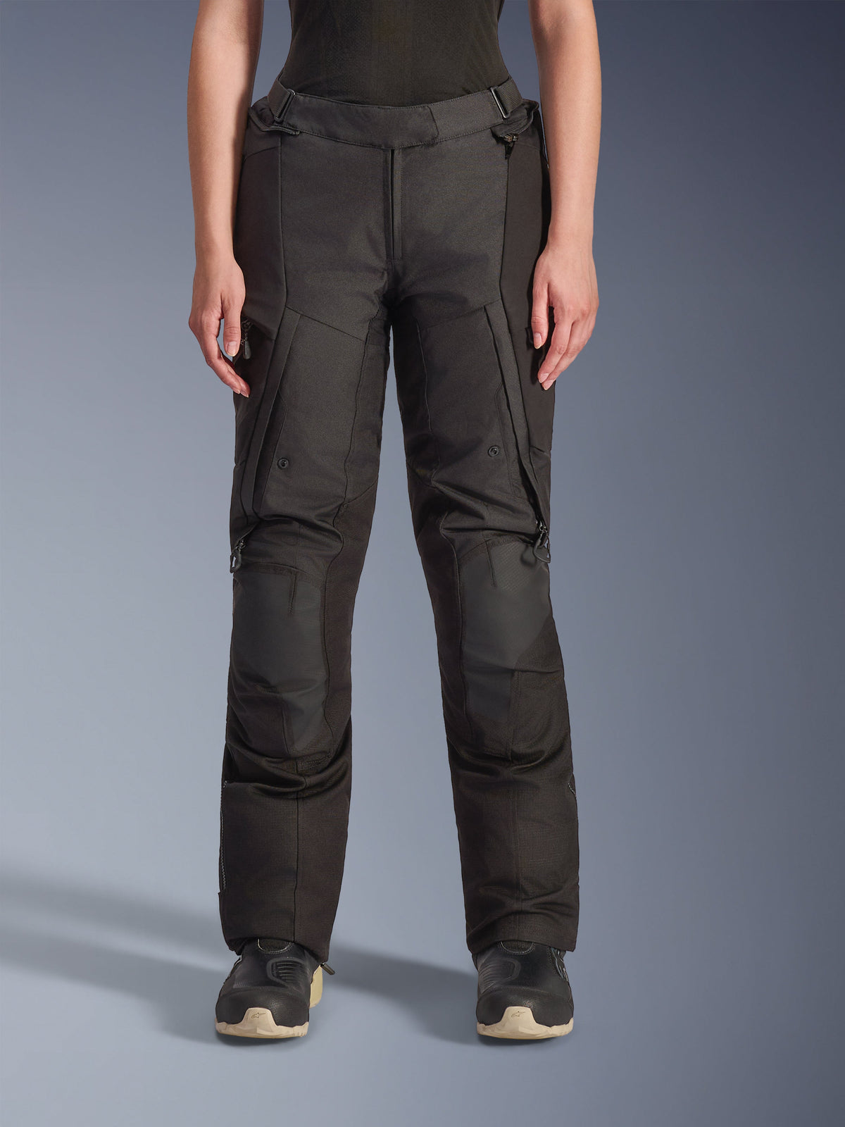 Alpinestars Stella Andes V4 Drystar Pants, pantaloni adventure touring da donna, neri, vista frontale, con pannelli rinforzati sulle ginocchia, tasche cargo resistenti all'acqua e cinghie regolabili in vita, indossati con stivali neri in studio.