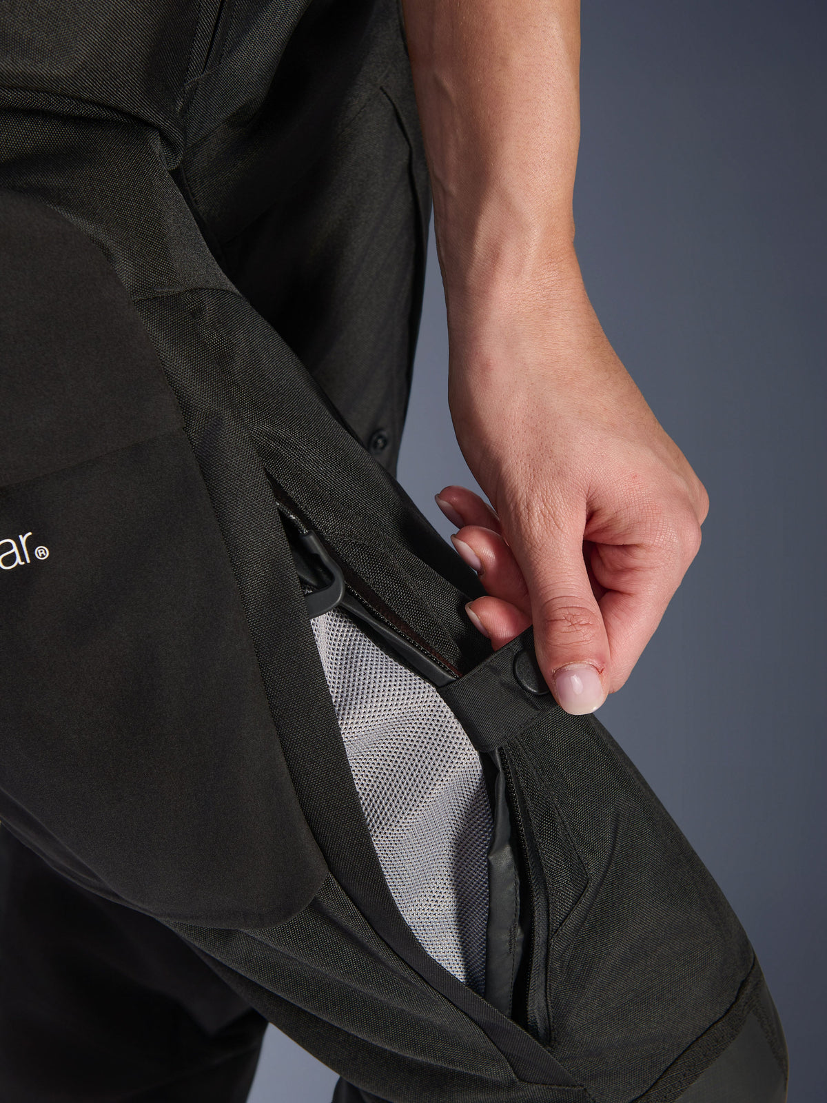 Alpinestars Pantaloni Stella Andes V4 Drystar® da donna, pantaloni da moto, nero, primo piano di una mano che apre la ventilazione con zip sulla coscia per rivelare la fodera in rete per il flusso d'aria, abbigliamento adventure in tessuto resistente