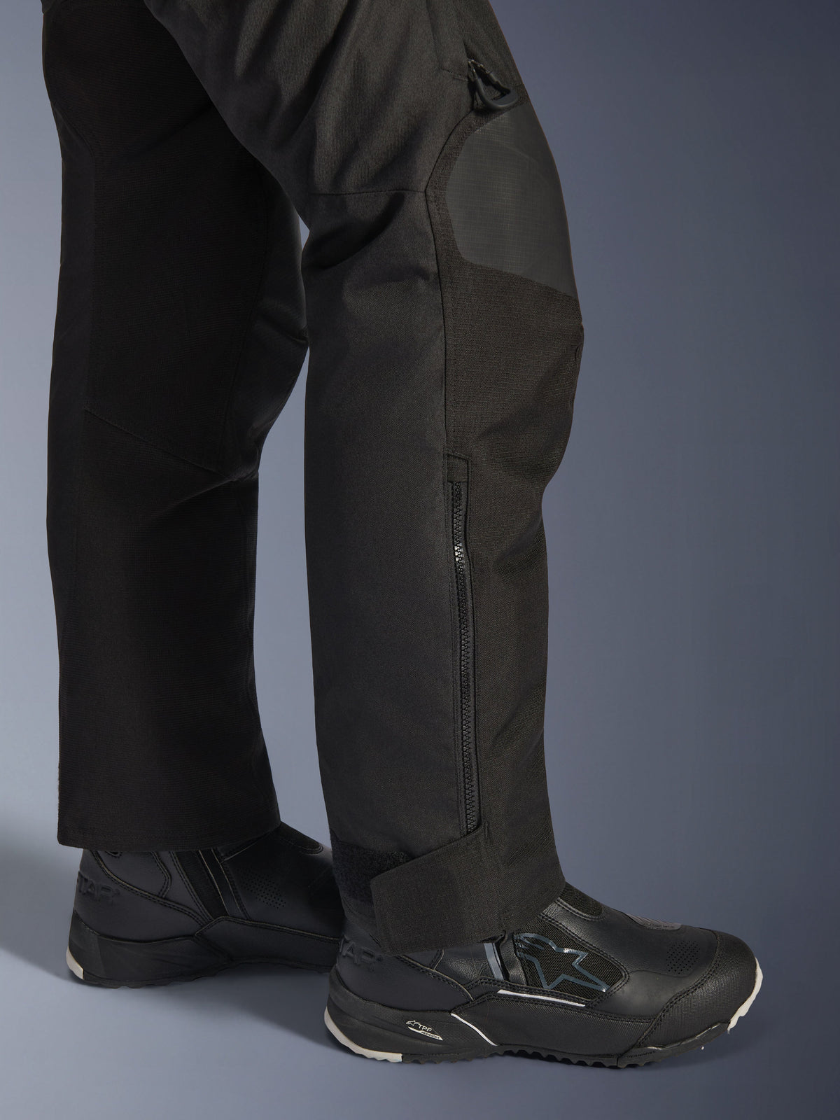 Alpinestars Stella Andes V4 Drystar® Pants, pantaloni da moto da donna, nero, dettaglio della parte inferiore della gamba con zip laterale e chiusura regolabile alla caviglia, indossati con stivali da moto Alpinestars neri