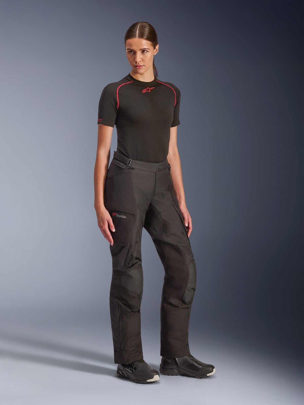 Pantaloni Alpinestars Stella Andes V4 Drystar®, neri, pantaloni da moto adventure touring da donna, indossati con un base layer nero a maniche corte e stivali da moto neri, dotati di tecnologia impermeabile Drystar e tasche cargo
