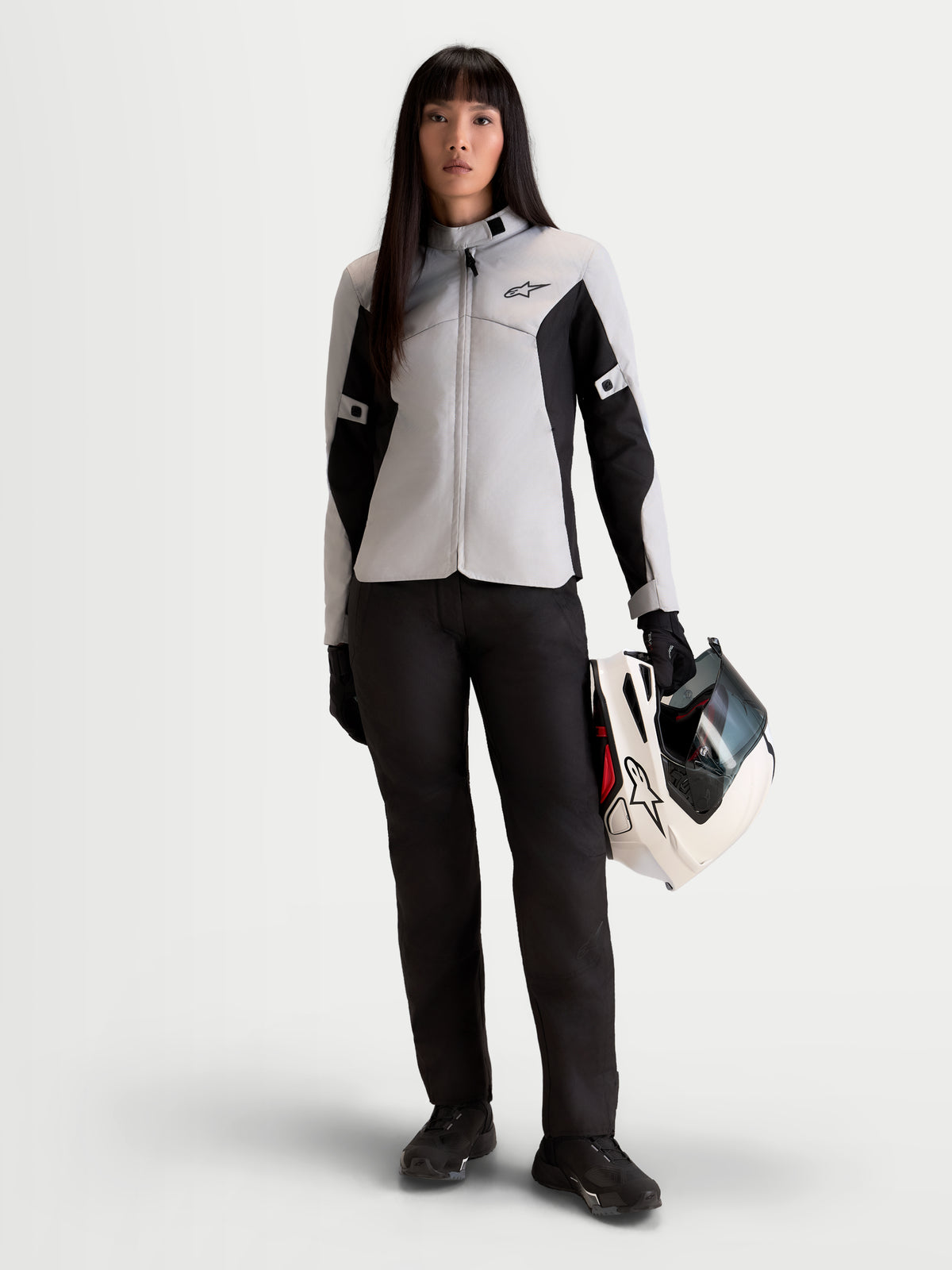 Alpinestars Stella C-1 Waterproof Pantaloni, pantaloni da moto urbani da donna in nero, vista frontale su una modella che indossa una giacca coordinata e tiene un casco, equipaggiamento di protezione certificato di classe A