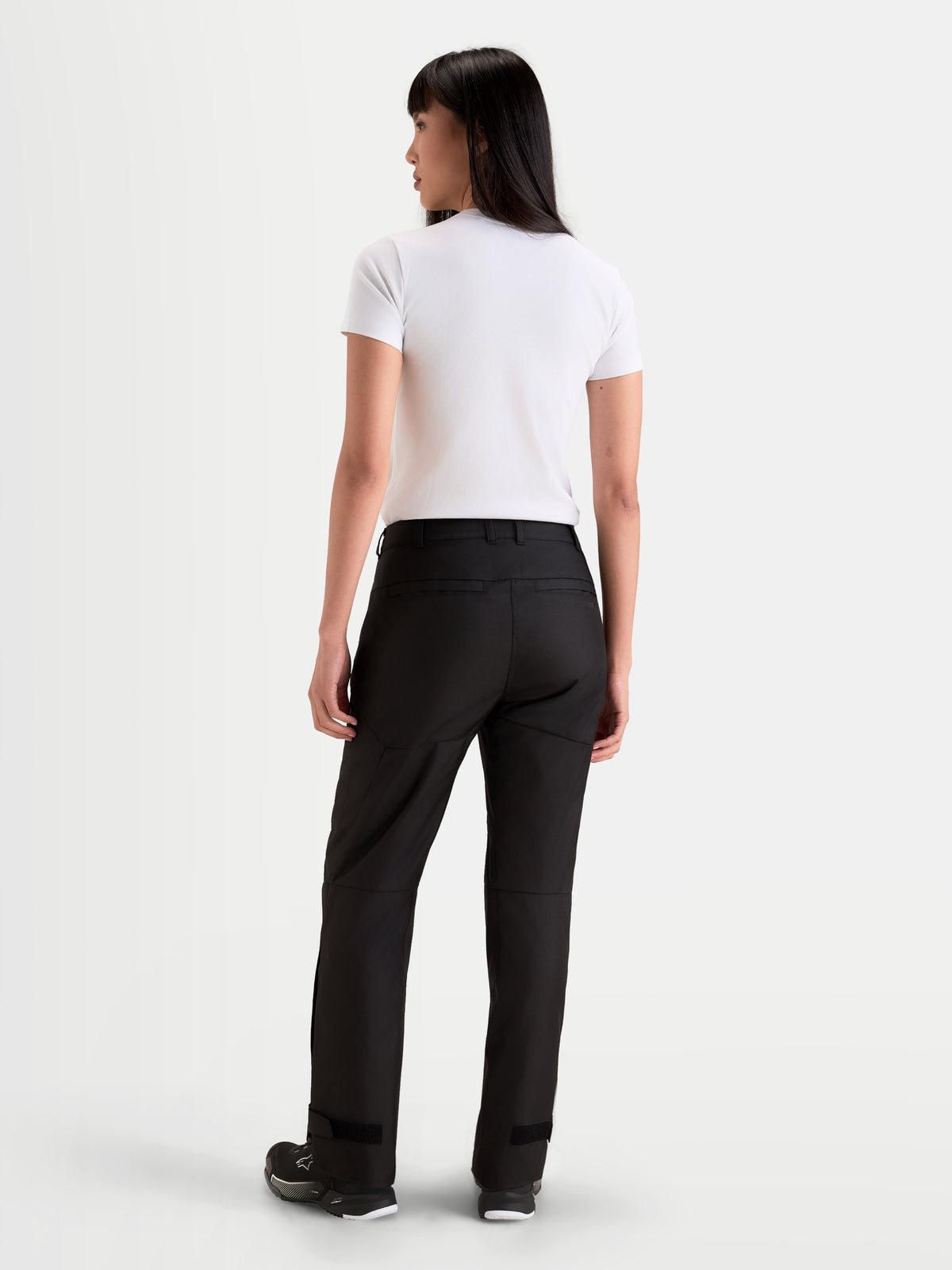 Alpinestars Stella C 1 Waterproof Pantaloni, pantaloni da moto urban da donna, nero, vista posteriore su una modella con t-shirt bianca e scarpe da moto, con struttura protettiva e impermeabile