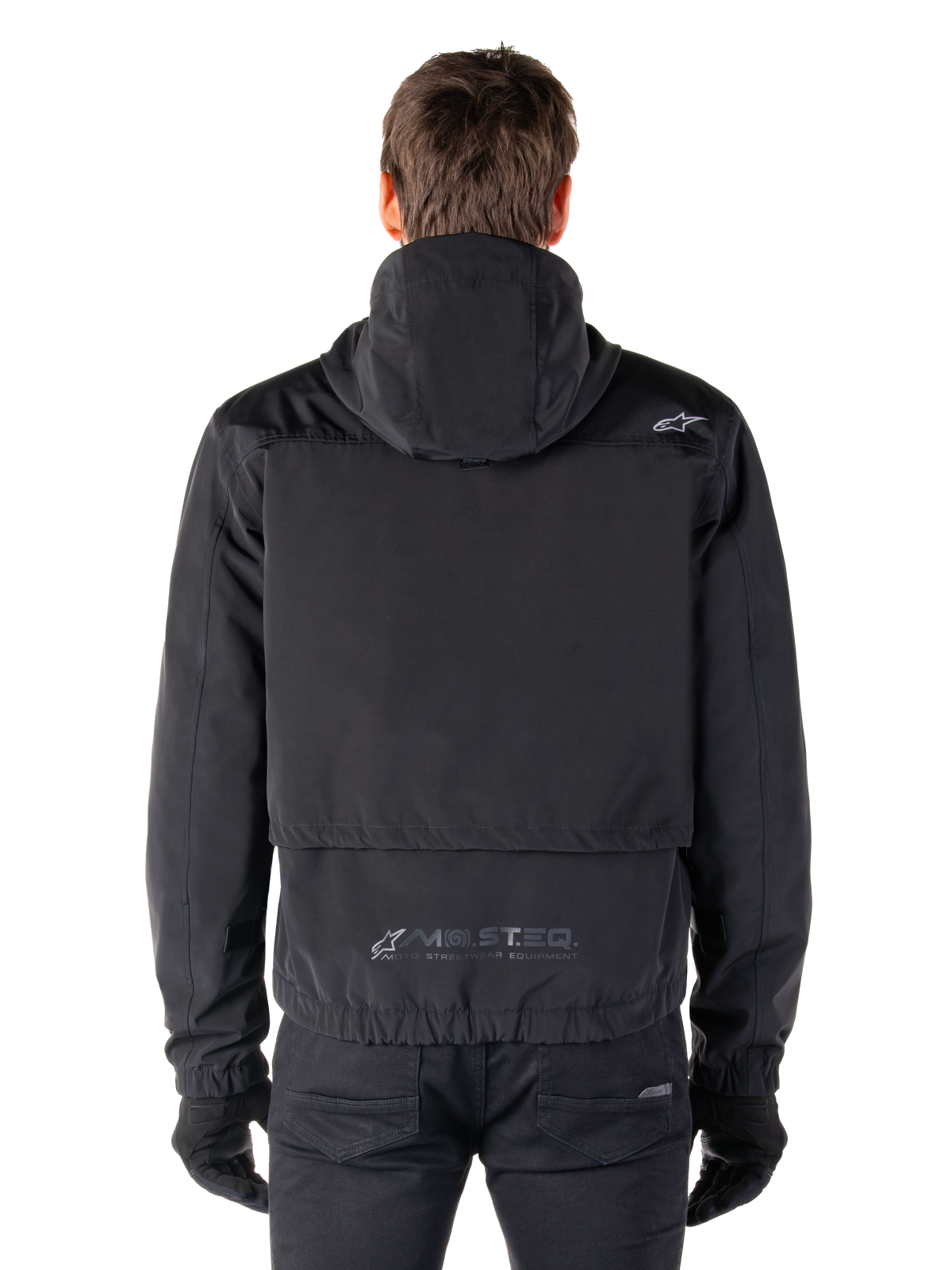 Alpinestars Mootant Waterproof Parka, giacca da moto nera, vista posteriore con cappuccio, piccolo logo Astar sulla spalla e marchio riflettente MO.ST.EQ. sulla parte bassa della schiena
