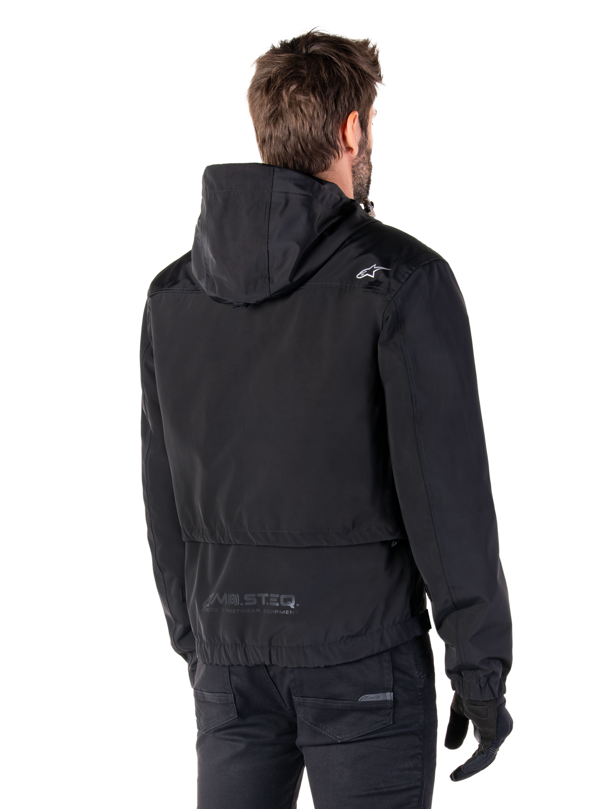 Alpinestars Mootant Waterproof Parka, giacca da moto nera, vista posteriore con design con cappuccio, logo bianco sulla spalla e marchio riflettente MO.ST.EQ. sulla parte bassa della schiena, abbigliamento tecnico urban contemporary