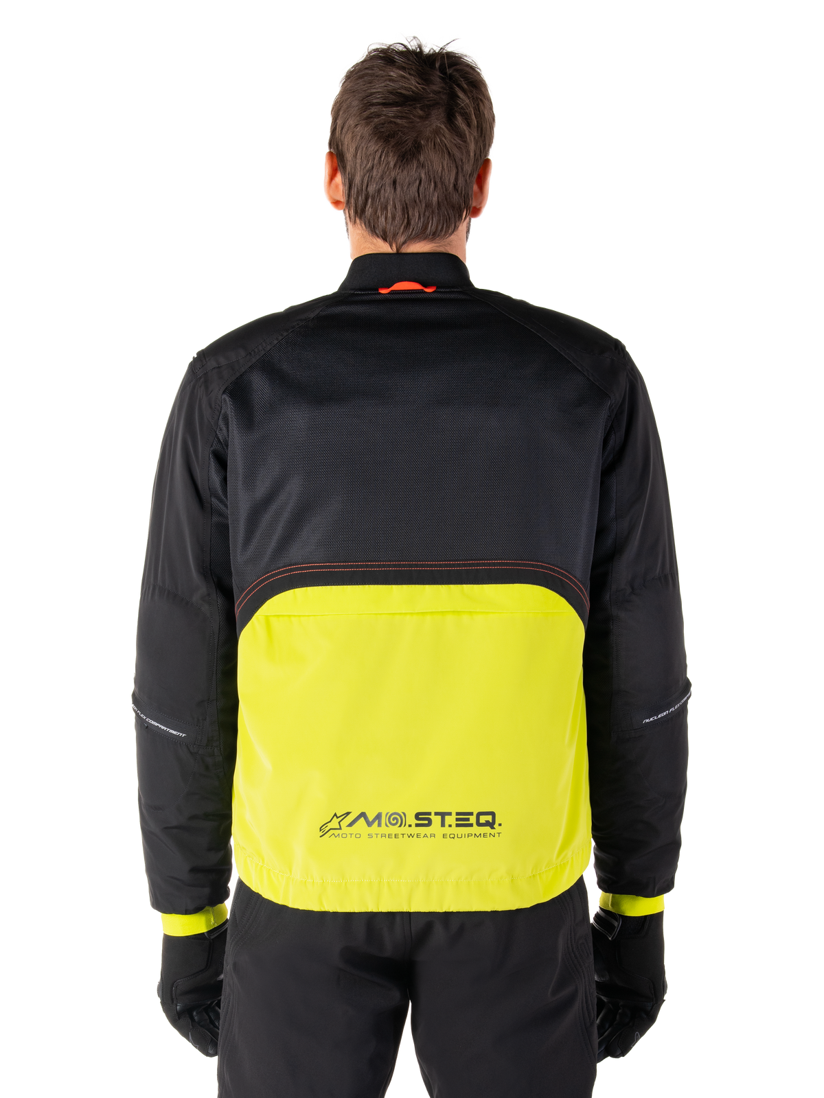 Alpinestars Mootant Waterproof Parka, giacca da moto, Lime Punch e nero, vista posteriore con parte superiore in rete nera per la ventilazione e sezione inferiore lime con logo MO.ST.EQ., indossata con pantaloni e guanti neri