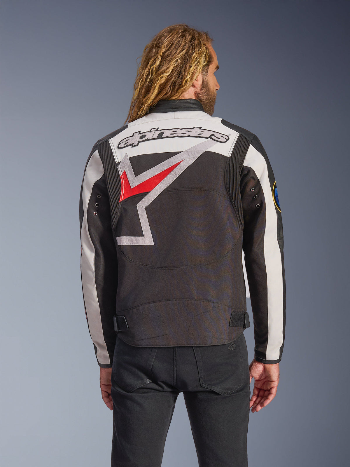 Giacca Alpinestars Axton, giacca da moto, nero, bianco sporco e rosso brillante, vista posteriore con un grande logo a stella avvolgente e scritta del marchio, design d'ispirazione vintage racing con pannelli a fisarmonica sulle spalle e regolatori in vita