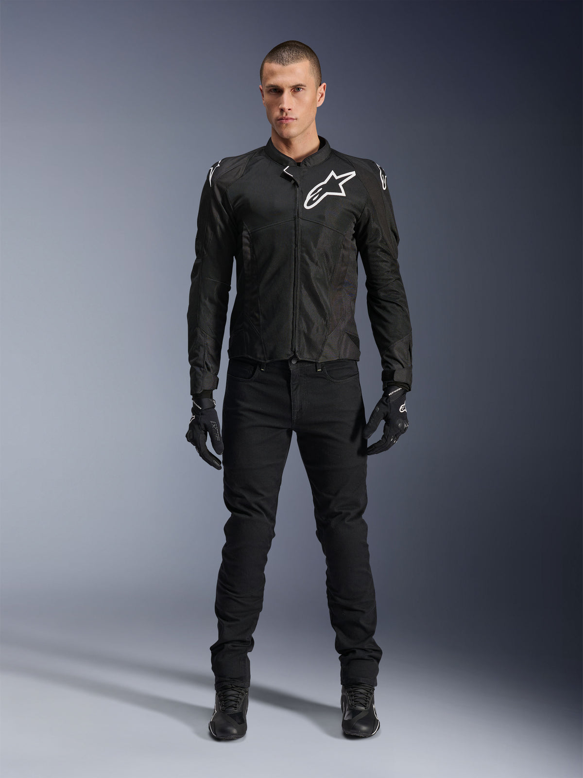 Giacca Alpinestars Viper Air V4, giacca da moto in tessuto nero, logo bianco su petto e spalle, indossata con pantaloni e guanti da moto neri, dotata di pannelli in rete tecnica per la ventilazione, vista in studio a figura intera