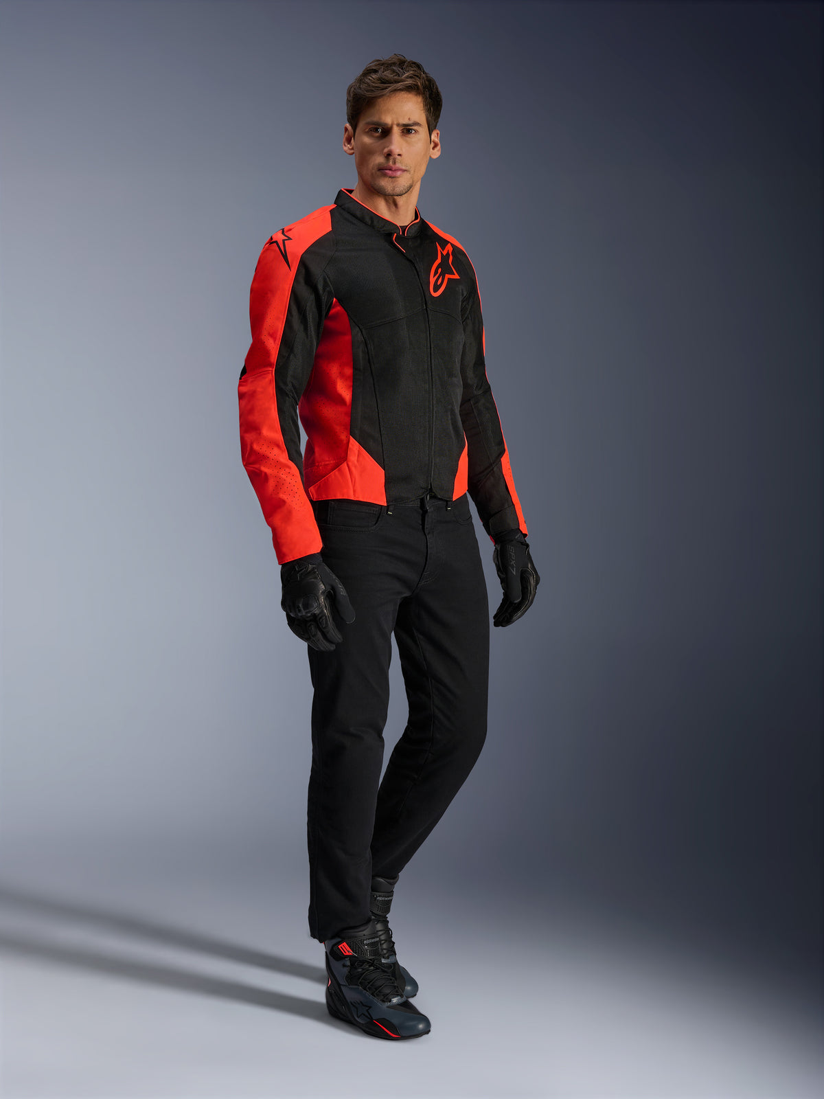 Giacca Alpinestars Viper Air V4, giacca da moto, rosso fluo e nero, indossata da un modello con jeans da moto neri, guanti neri e scarpe da moto, design in tessuto mesh con vivaci pannelli rossi e logo a stella, abbigliamento sportivo da strada