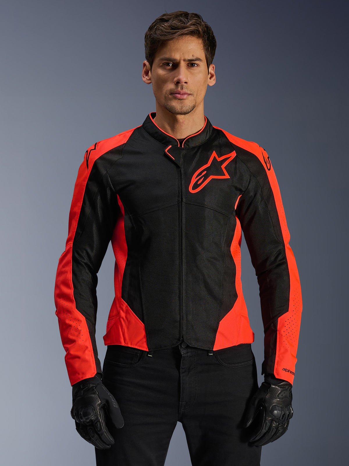 Giacca Alpinestars Viper Air V4, giacca da moto racing, rosso fluo e nero, indossata da un modello con guanti neri, pannelli in mesh tecnico per la ventilazione, design sportivo con logo Alpinestars a stella sul petto