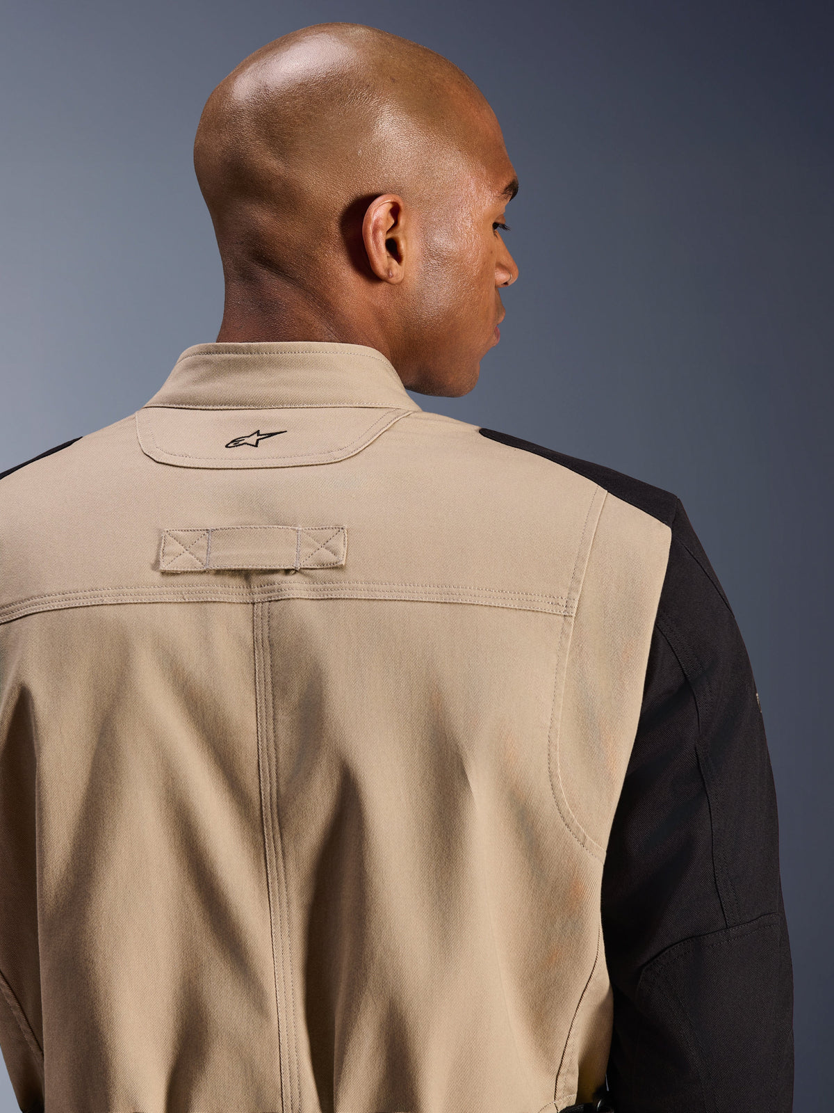 Giacca Alpinestars Dice, giacca da moto urbana, tan e nero, dettaglio ravvicinato del colletto posteriore e della spalla, con logo ricamato, robusta costruzione in twill di policotone, stile workwear urbano