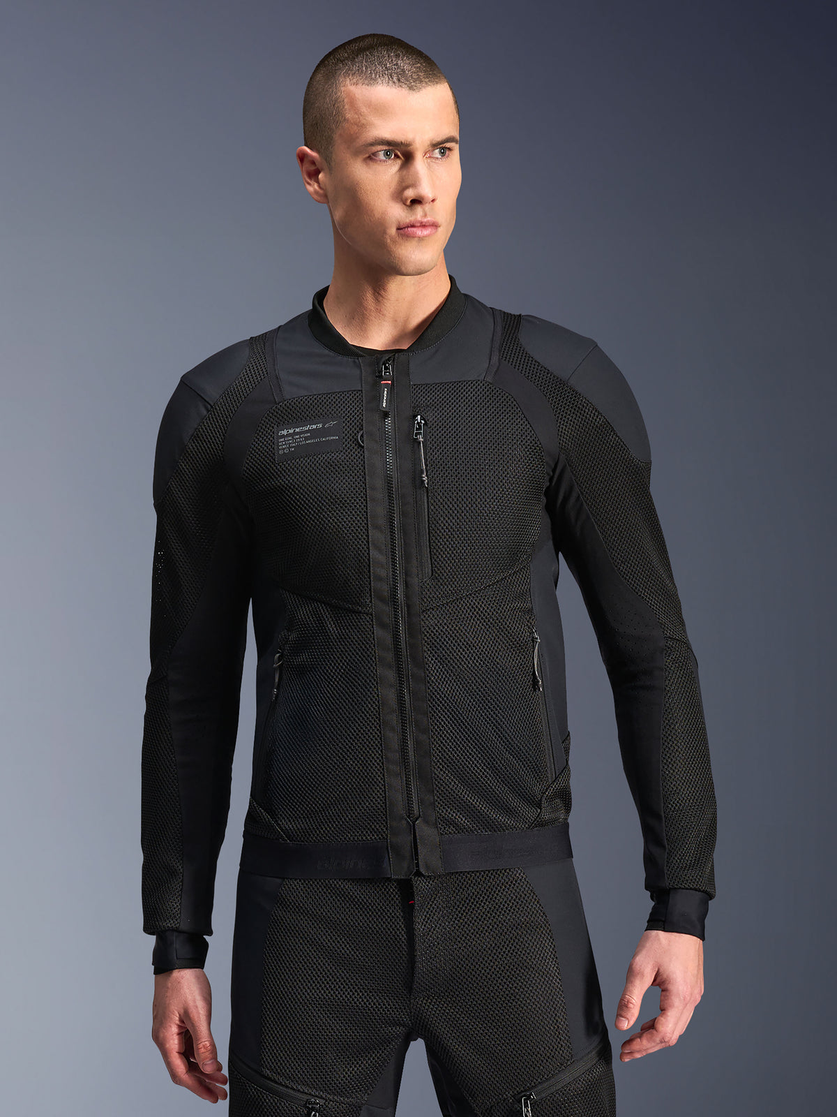 Alpinestars Troop-Air Pro Jacket, giacca da moto in mesh nera, modello maschile che indossa una giacca protettiva traforata con struttura in mesh tecnico 2D, zip frontale, tasche con zip, abbigliamento tecnico da moto