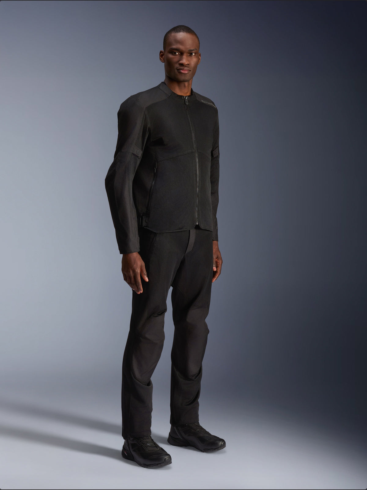 Giacca Alpinestars C-1 Air, nero, indossata da un modello con pantaloni e scarpe da moto neri coordinati, con ampi pannelli in rete tecnica per il flusso d'aria, estetica urban pulita e vestibilità lineare.