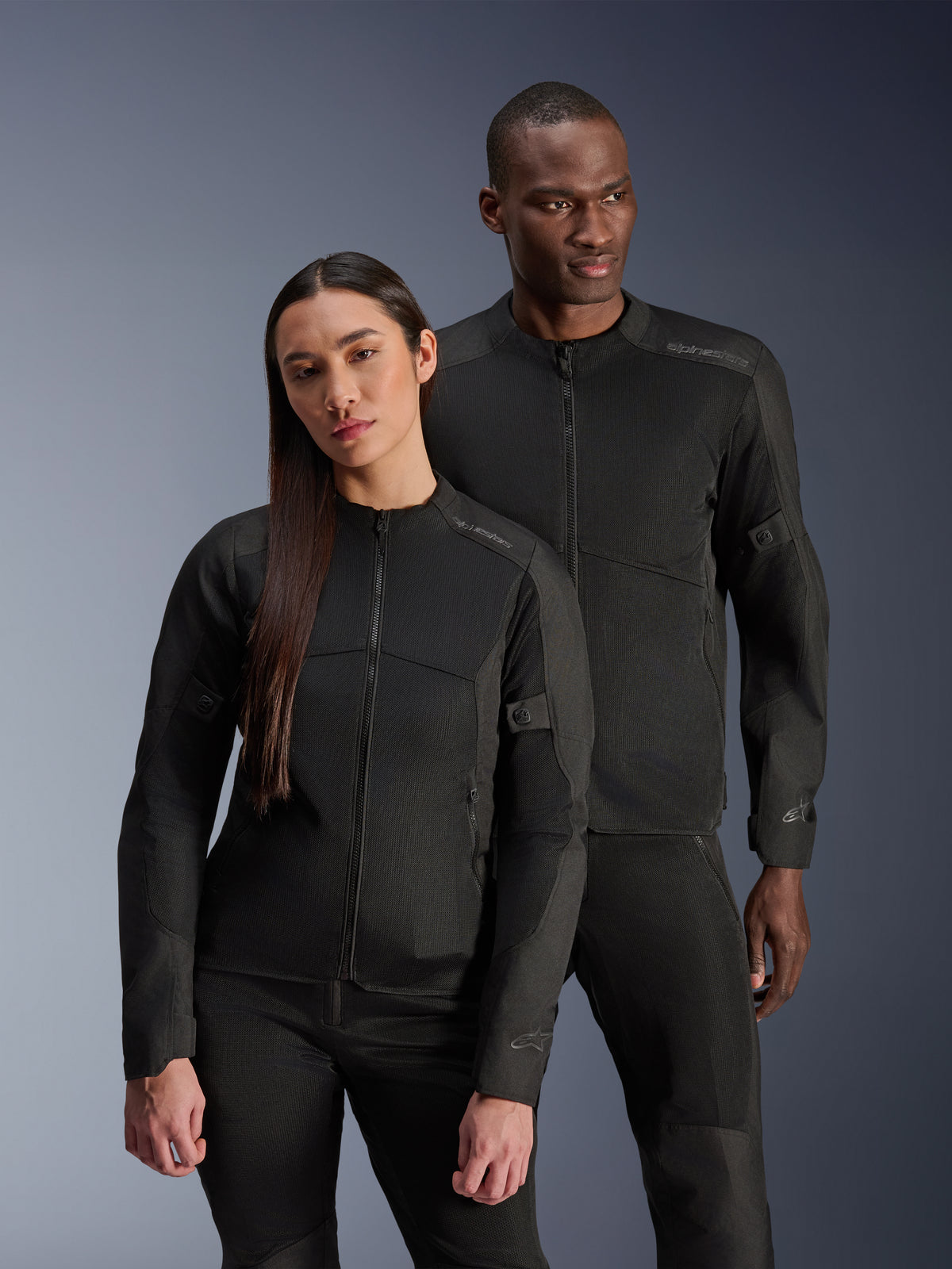 Giacca Alpinestars Stella C-1 Air, nero, indossata da un modello e una modella, costruzione in mesh tecnico per il flusso d'aria, loghi riflettenti, abbigliamento da moto urbano elegante