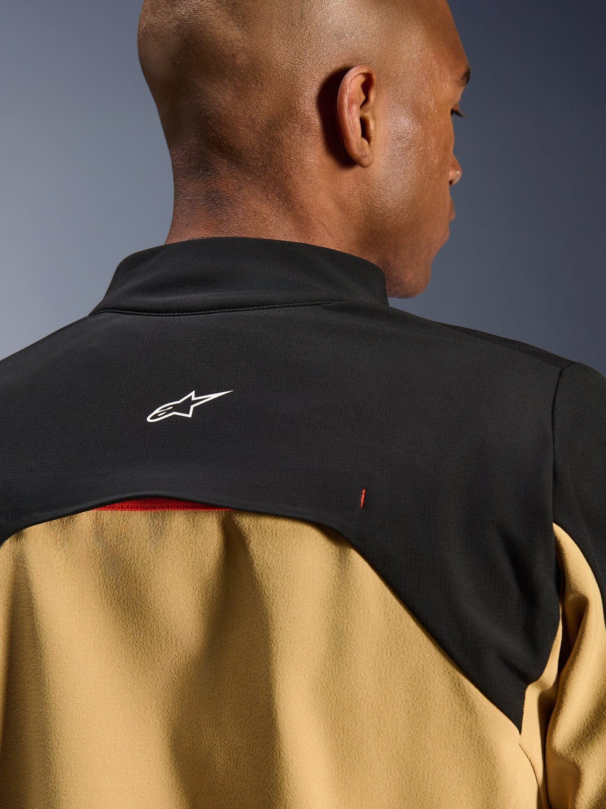 Giacca Alpinestars Provoke, giacca da moto urbana, nero e camel, primo piano della parte superiore della schiena e del colletto con logo Astars bianco su carré nero e pannelli inferiori color cammello, design tecnico contemporaneo ispirato all'outdoor