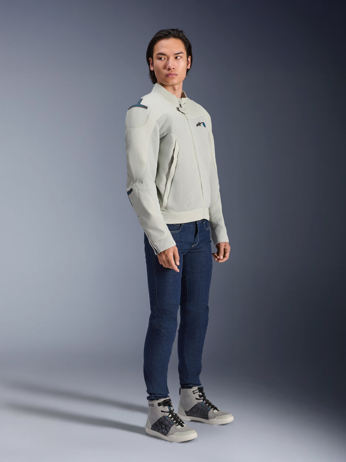 Giacca Alpinestars Circal-1 Air in Metal Gray e Methyl Blue, indossata da un modello con jeans blu scuro e sneakers grigie, giacca da moto estiva urbana con ampi pannelli in mesh per il flusso d'aria e un design minimalista.