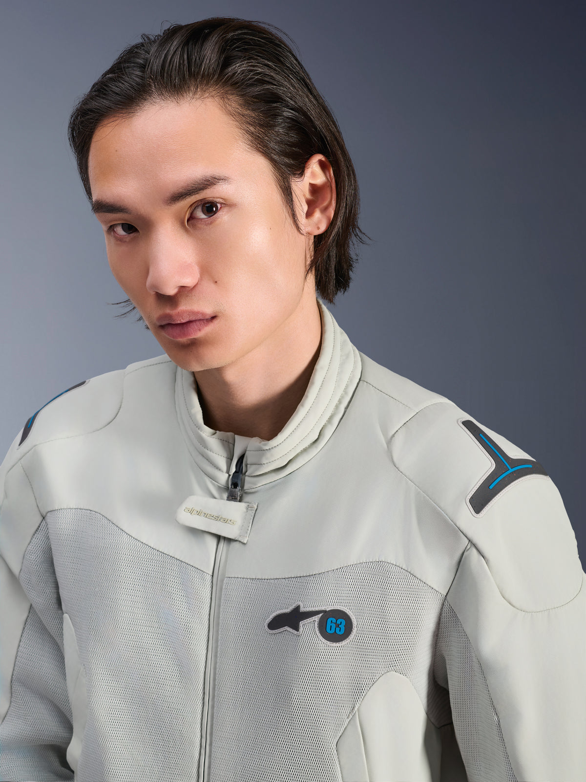 Giacca Alpinestars Circal-1 Air, grigio metallo con accenti blu metile, modello maschile che indossa una giacca da moto urbana estiva, primo piano dei pannelli in mesh per la ventilazione e branding minimalista sul petto
