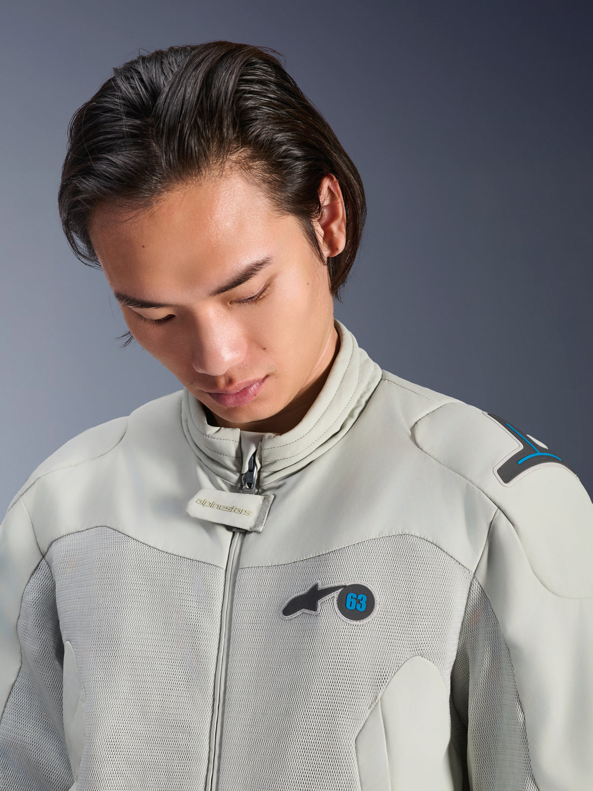 Modello che indossa la giacca Alpinestars Circal-1 Air in Metal Gray con accenti Methyl Blue, vista ravvicinata che mette in risalto il colletto, i pannelli in rete sul petto e il logo minimalista, abbigliamento da moto urbano sostenibile.