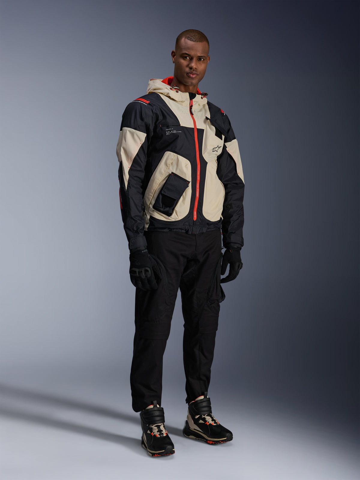 Pantaloni Alpinestars Acteon, pantaloni da moto neri, indossati con giacca Mogress Air nera, beige e rossa, guanti da moto neri e sneaker da moto alte coordinate, abbigliamento da moto urban contemporaneo da uomo