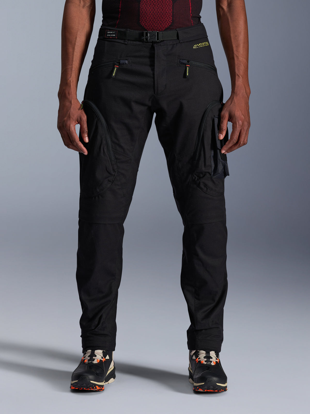 Alpinestars Acteon Pants, pantaloni da moto urban neri, vestibilità regular affusolata con tasche cargo laterali e cerniere a spirale rovesciata, cintura in vita integrata e branding giallo, abbigliamento protettivo da moto in tessuto