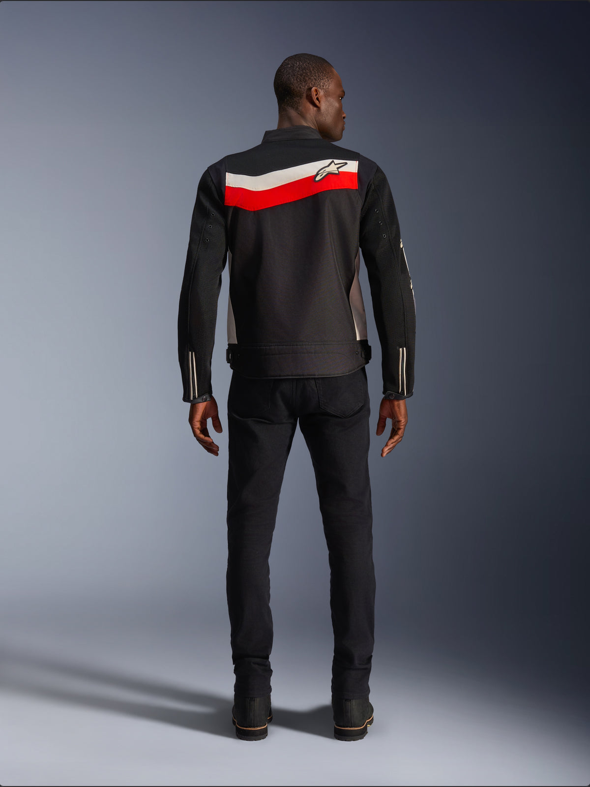 Alpinestars T-Dyno Air Jacket, giacca da moto in tessuto da uomo, vista posteriore, nera con strisce orizzontali rosso acceso ed ecru sulla schiena, logo Alpinestars sul giogo, indossata con pantaloni e stivali neri, costruzione in mesh 3D traspirante