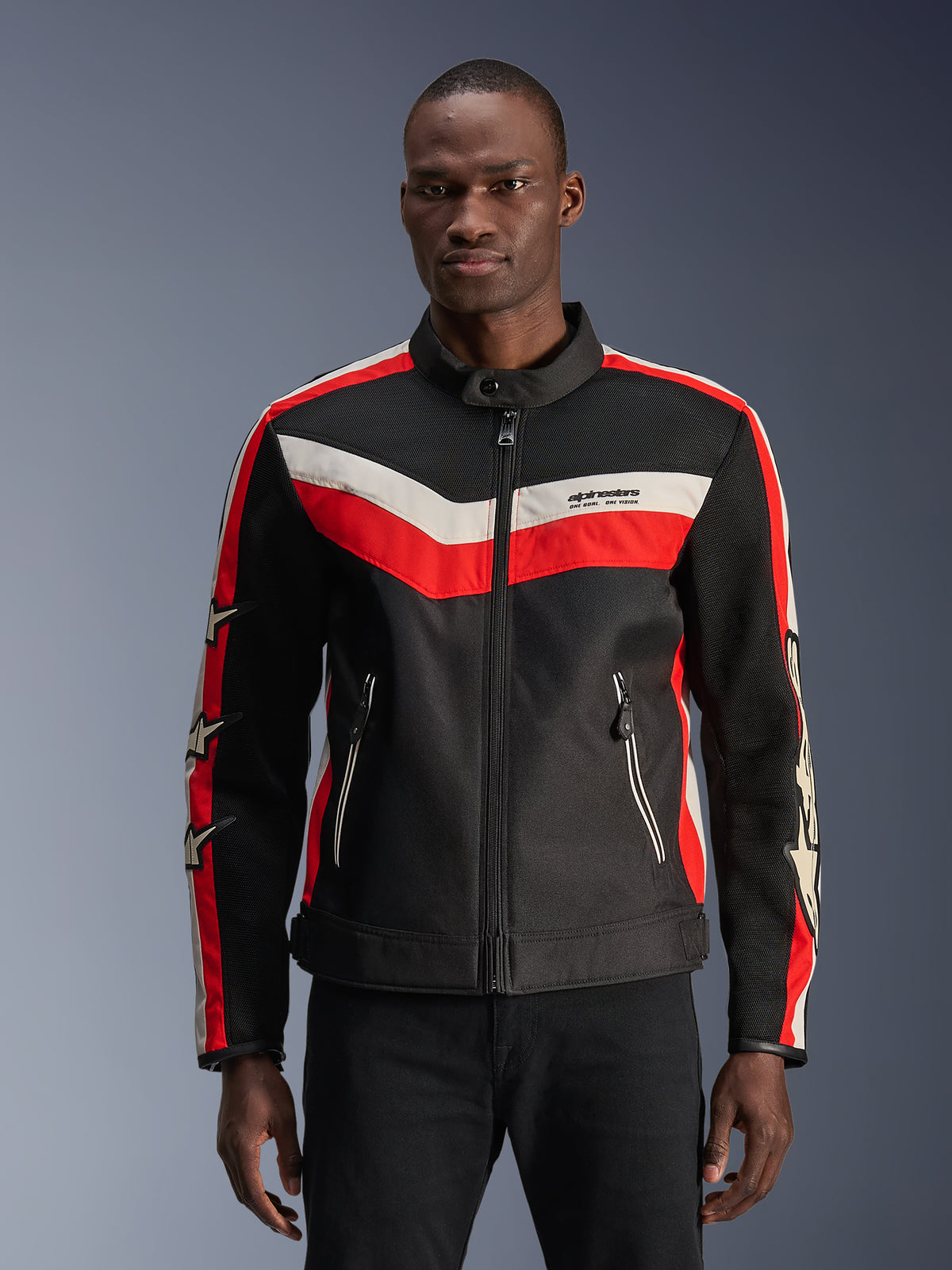 Alpinestars T-Dyno Air Jacket, nera con strisce a chevron rosso brillante ed ecru, con dettagli a stella sulle maniche, colletto alto con cerniera frontale, tasche con zip, design di giacca da moto in tessuto d'ispirazione vintage