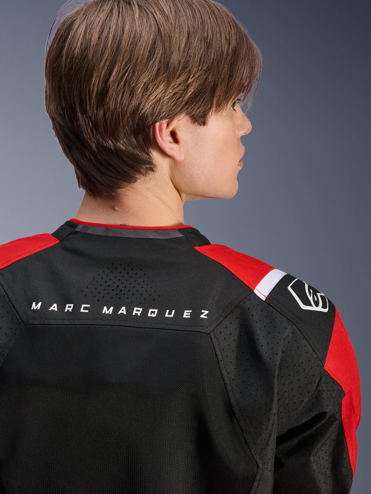 Giacca Alpinestars MM93 T-SPS Air V2, vista posteriore della parte superiore della schiena e delle spalle, nero con dettagli rosso brillante e bianco, scritta 'MARC MARQUEZ' sullo sprone, caratterizzata da pannelli in rete tecnica e logo sulla spalla, abbigliamento moto urban sport