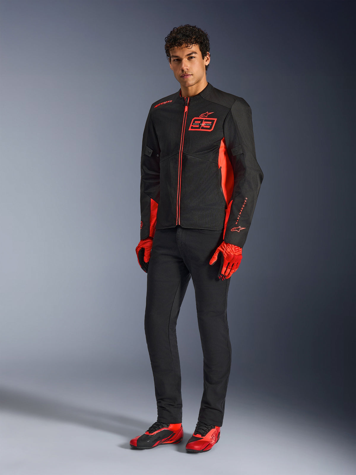 Giacca Alpinestars MM93 C-1 Air, giacca da moto, rosso fluo, rosso brillante e nero, indossata con guanti rossi, pantaloni neri e scarpe da moto rosse, con marchio MM93 e struttura leggera in mesh, abbigliamento urban contemporary