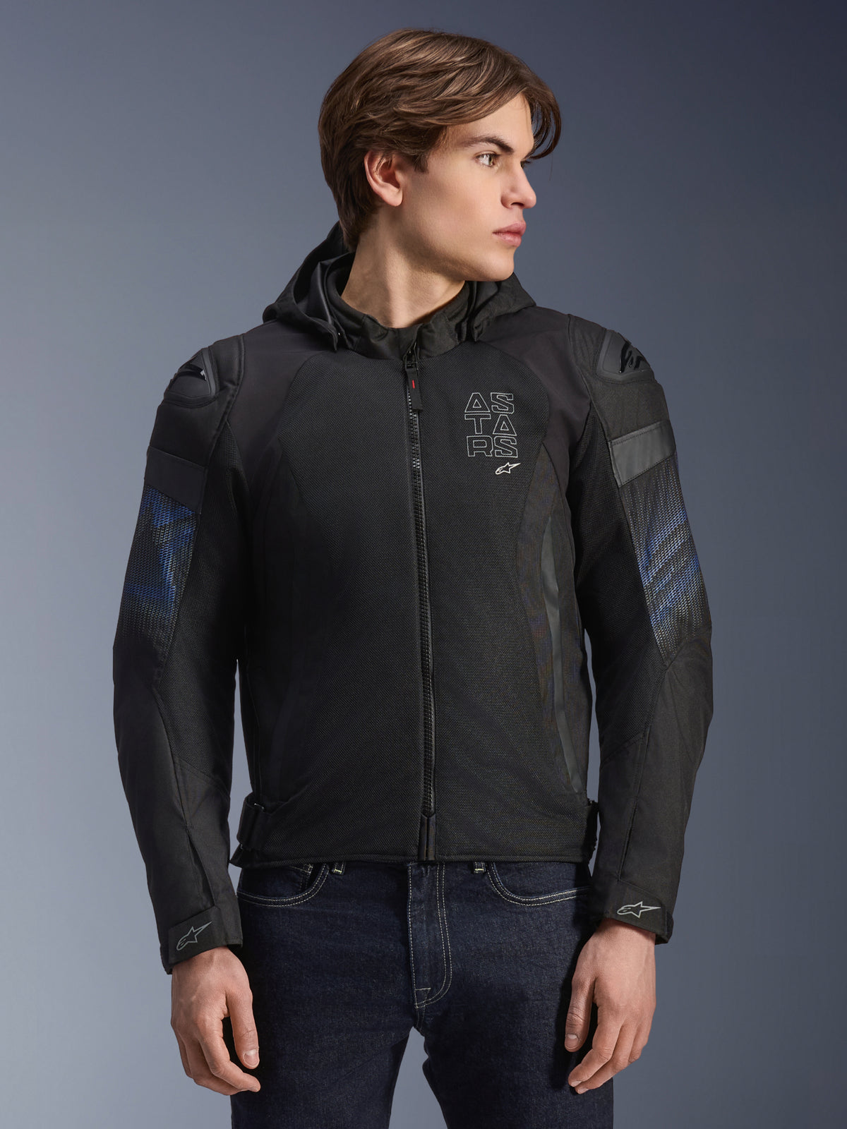 Alpinestars Zaca Air Venom WP Jacket, giacca da moto in tessuto, nero e blu elettrico, con cappuccio rimovibile e pannelli in rete 3D per la ventilazione, dotata di slider per spalle DFS Lite e marchio ASTARS sul petto, indossata da un modello, abbigliamento urban di ispirazione sportiva