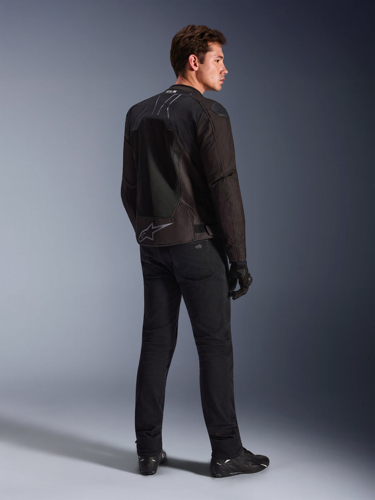 Giacca Alpinestars SMX Air in Black Anthracite, vista posteriore su modello, con marchio Tech-Air® Ready sul colletto e logo Astar sulla parte inferiore della schiena, indossata con pantaloni da moto e scarpe neri.