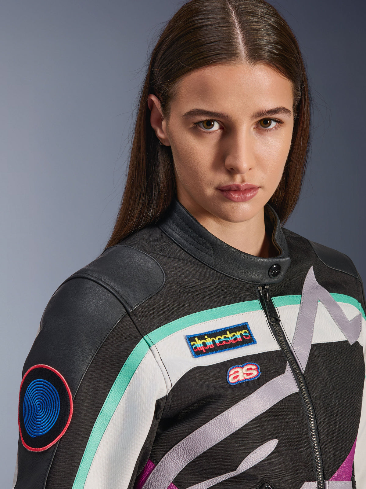 Giacca da donna Alpinestars Idles, giacca da moto, nero, bianco sporco e viola con accenti color ottanio, primo piano con patch colorate Alpinestars heritage e dettagli in pelle di capra sulle spalle, design d'ispirazione vintage per la guida urbana