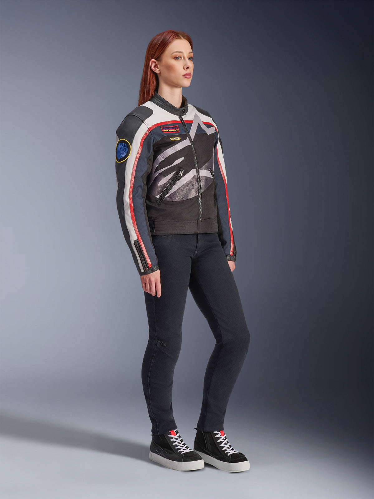 Giacca da donna Alpinestars Idles, giacca da moto, bianco avorio, rosso fiamma e nero, con un grande logo Alpinestars avvolgente e patch d'ispirazione racing vintage, indossata con pantaloni neri e sneakers alte, abbigliamento da moto urbano contemporaneo