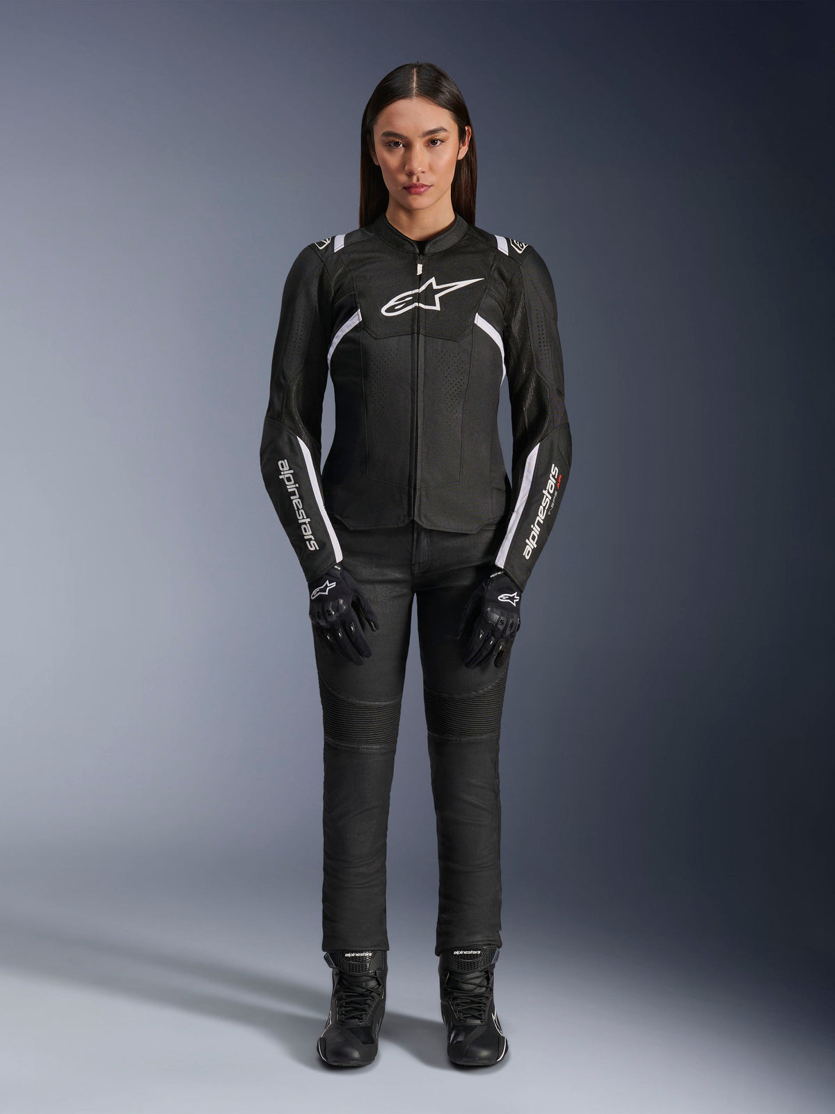 Giacca Alpinestars Stella T-Sps Air V2, giacca da moto da donna, nera e bianca, con pannelli in mesh e dettagli bianchi, indossata con pantaloni neri, guanti e stivali, vestibilità sportiva per la guida urbana