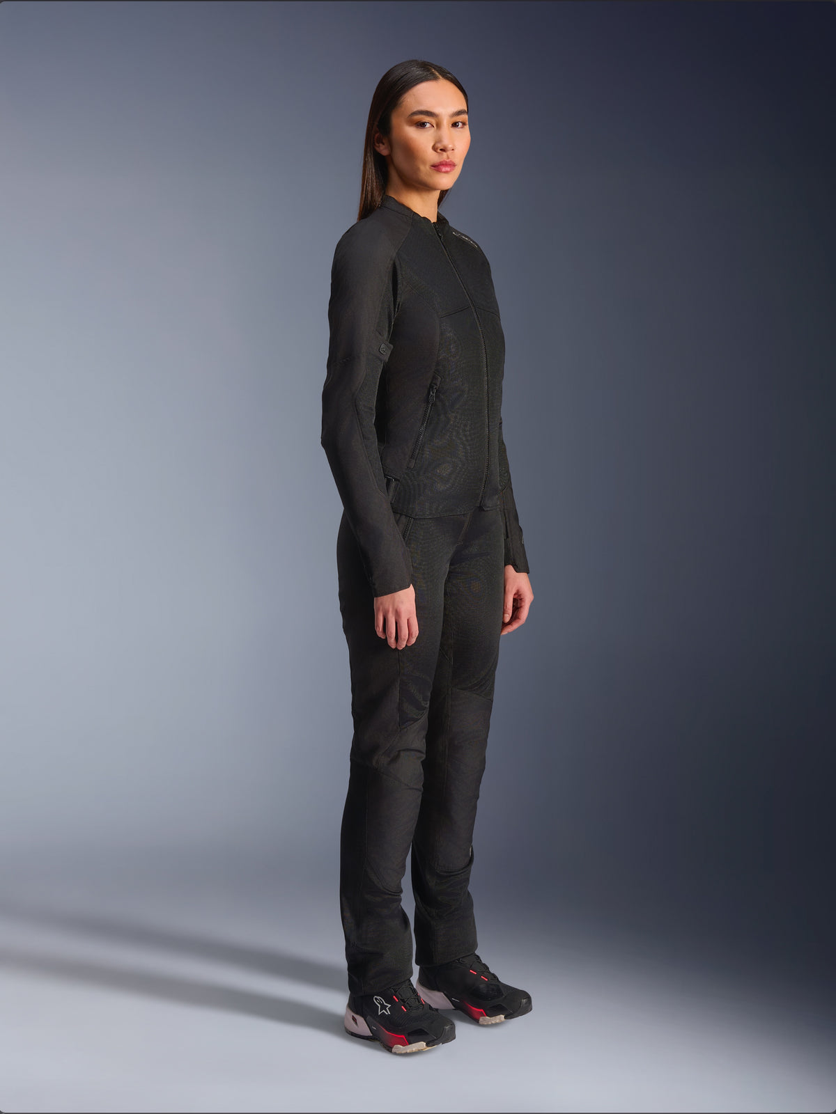Giacca Alpinestars Stella C-1 Air da donna in nero, giacca da moto in tessuto con pannelli in rete, indossata con pantaloni da guida neri coordinati e sneakers tecniche, scatto in studio che mostra un outfit completo per la guida urbana