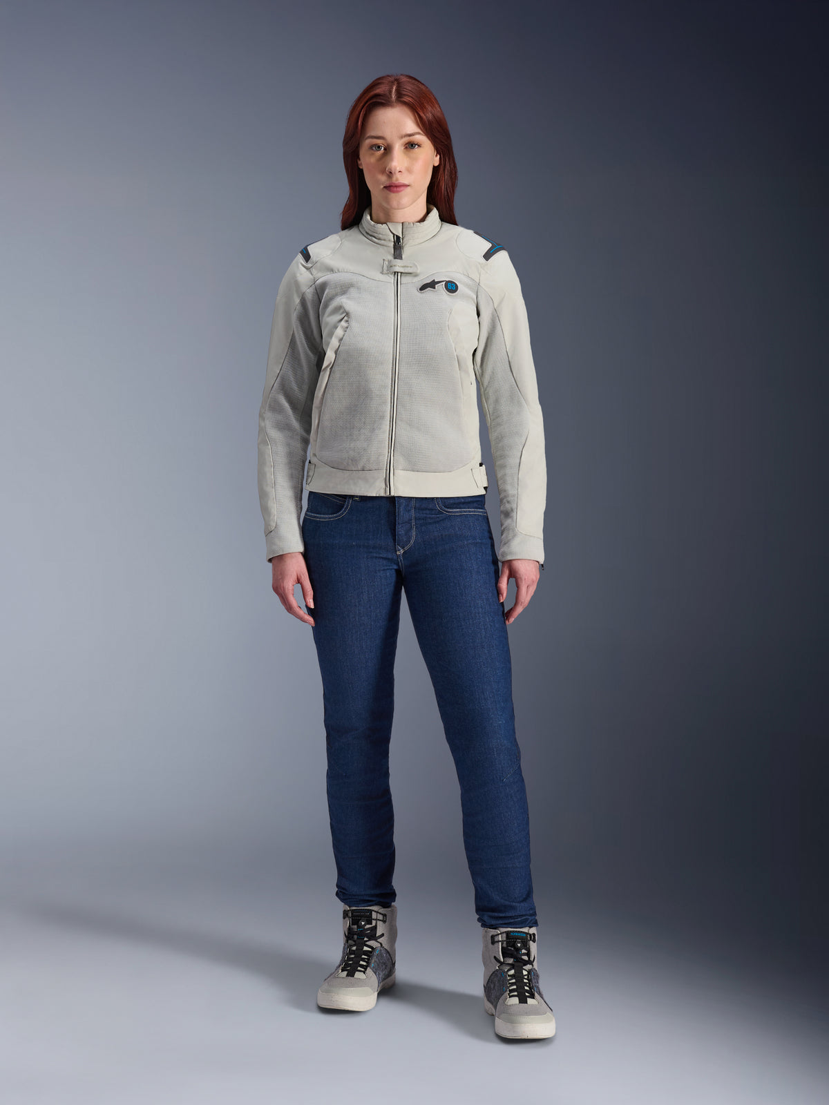 Giacca Alpinestars Stella CIRCAL-1 Air, giacca da moto da donna, grigio metallo e blu metile, indossata con jeans blu scuro e stivali da moto grigi, con pannelli in rete per la ventilazione e un design urbano moderno