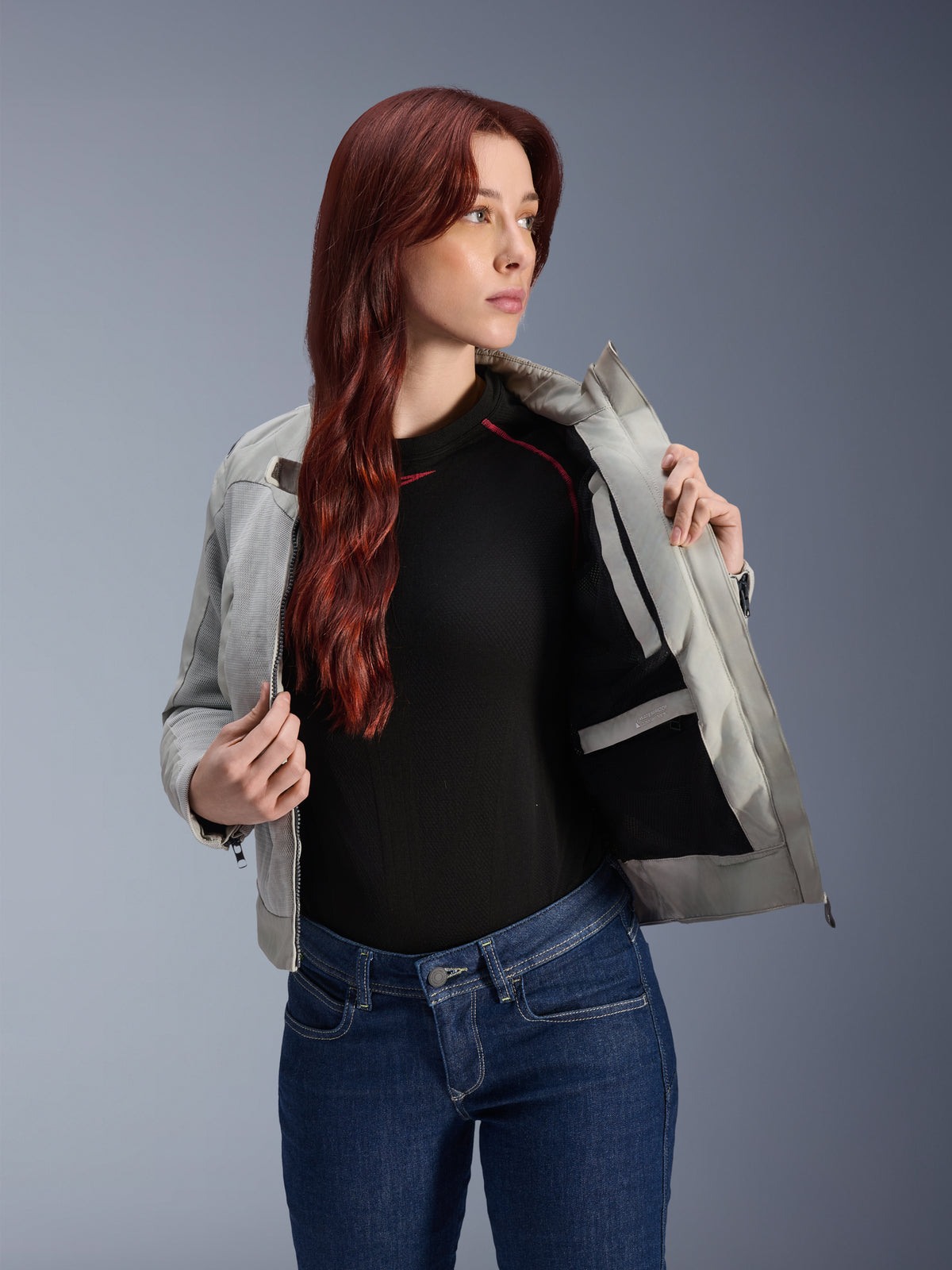 Giacca Alpinestars Stella Circal-1 Air in Metal Gray, modella che apre la giacca per mostrare la fodera interna in rete e la tasca, indossata con jeans blu e top nero, abbigliamento da moto urbano contemporaneo
