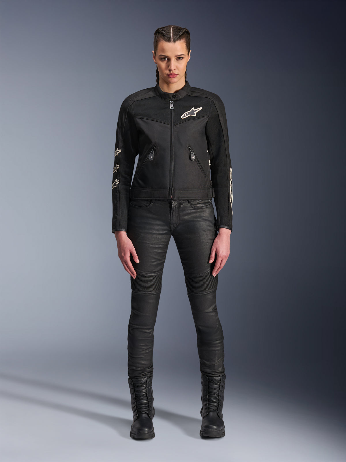Modella con giacca Alpinestars Stella T-Dyno Air, giacca da moto da donna in nero, con pannelli in rete 3D e loghi Astars bianchi, abbinata a pantaloni da moto slim-fit neri e stivali stringati neri, stile urban riding