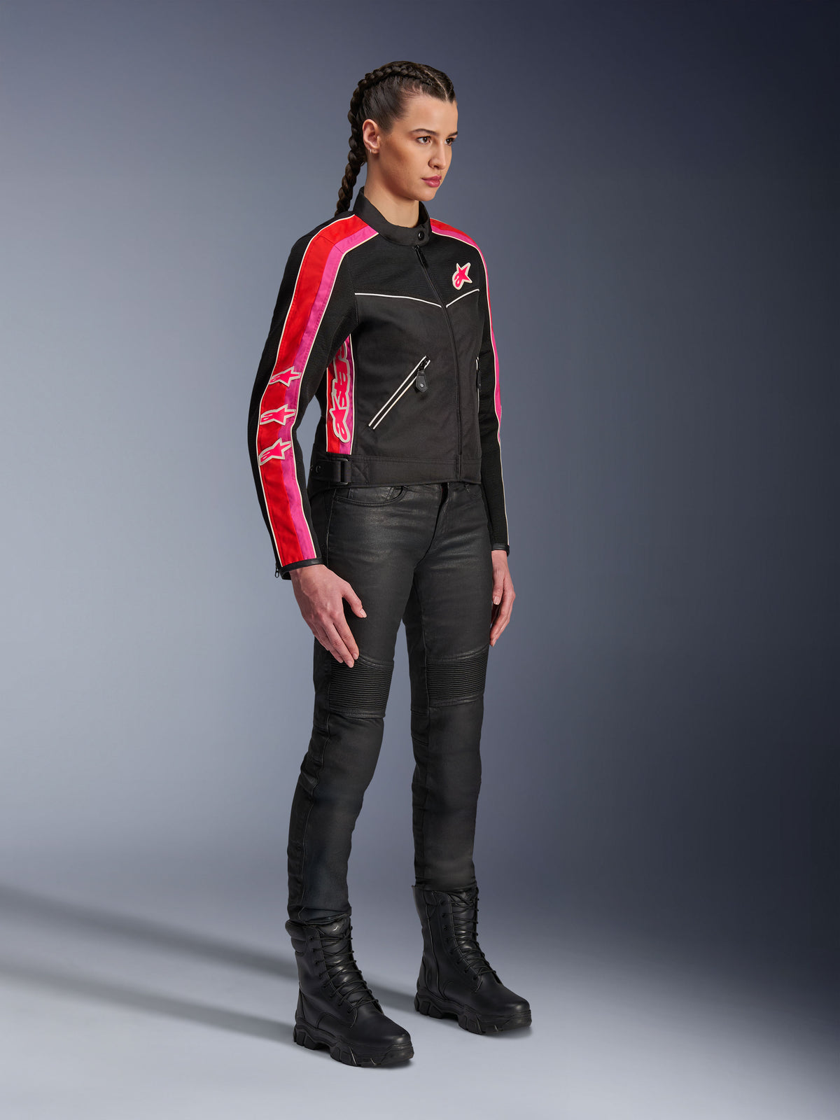 Alpinestars Stella T-Dyno Air Jacket, giacca da moto da donna, nero con strisce rosso acceso e fucsia sulle maniche, indossata con pantaloni da moto e stivali neri, design in rete d'ispirazione vintage per la guida urbana