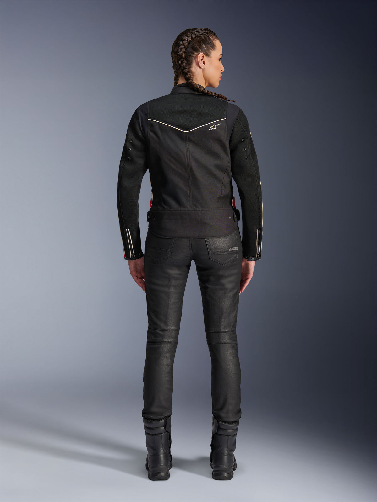 Alpinestars Stella T-Dyno Air Jacket, vista posteriore, giacca da moto da donna nera con profili bianchi e piccolo logo a stella, indossata con pantaloni tecnici neri e stivali da moto, vestibilità biker elegante per la guida urbana su strada