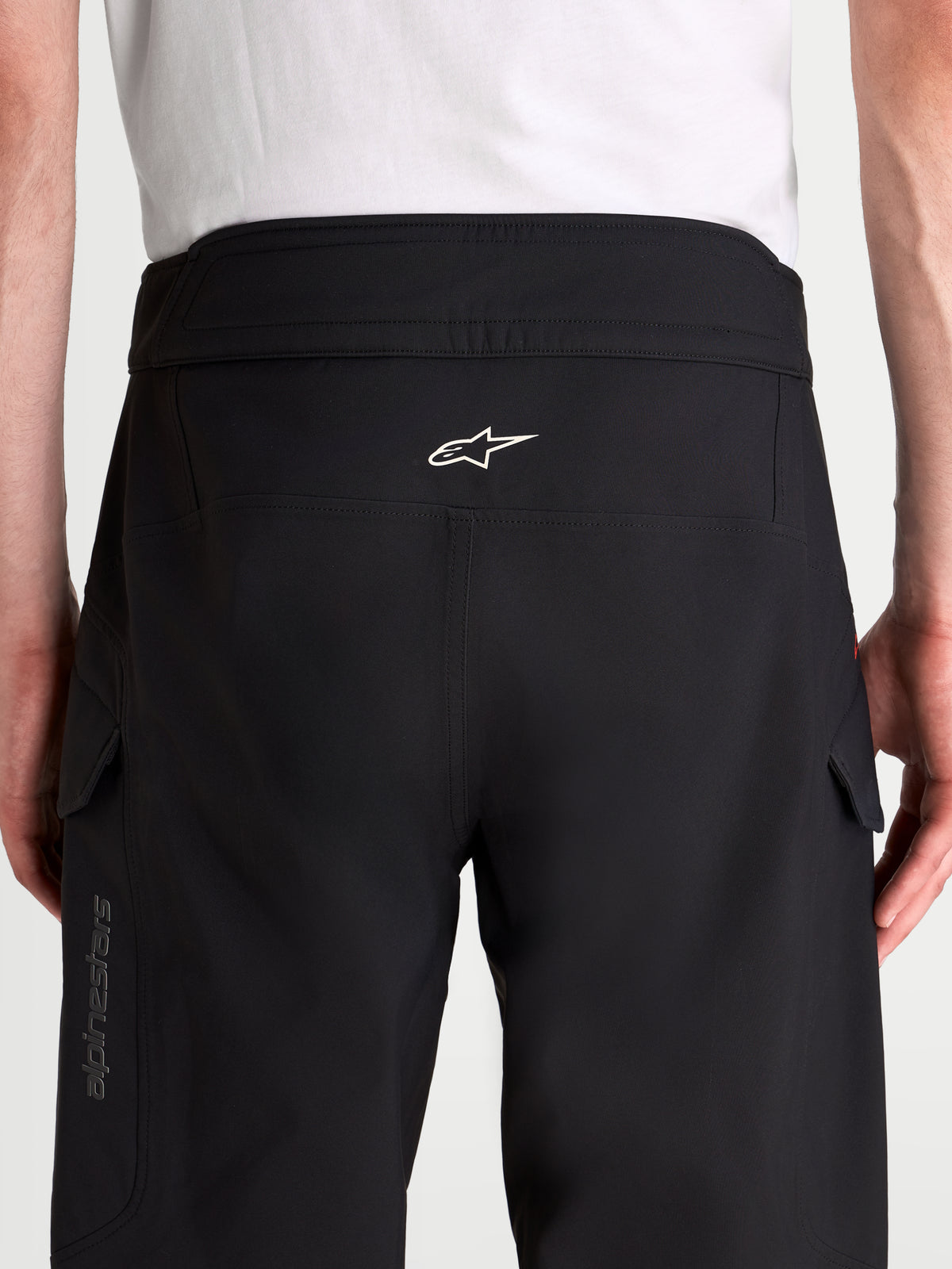 Alpinestars Juggernaut V2 Drystar Pantaloni, pantaloni da moto urbani impermeabili da uomo, nero, vista posteriore con cintura rialzata, struttura ergonomica della seduta, logo Alpinestars bianco e tasche cargo laterali indossati da un modello
