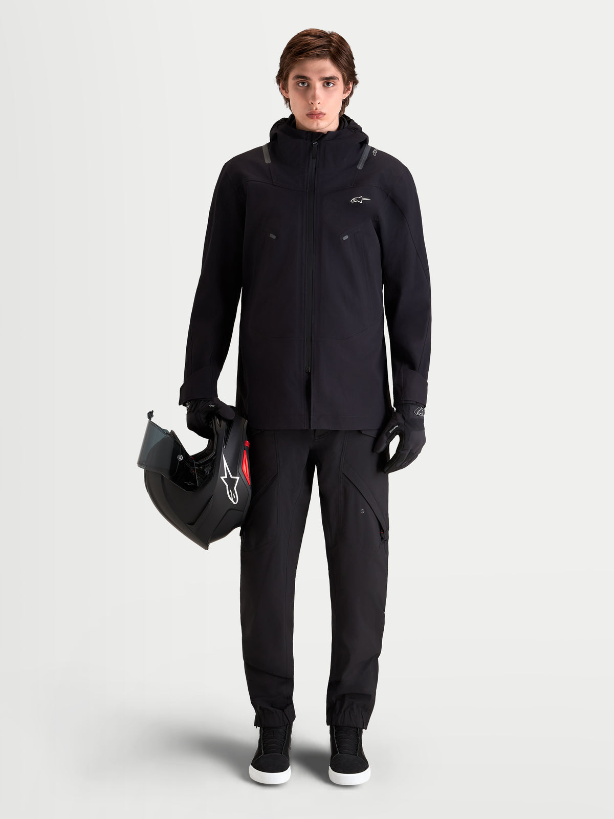 Alpinestars Juggernaut V2 Drystar Pantaloni, pantaloni da moto urban contemporary da uomo in nero, vista frontale a figura intera su un modello che indossa una giacca coordinata e tiene un casco